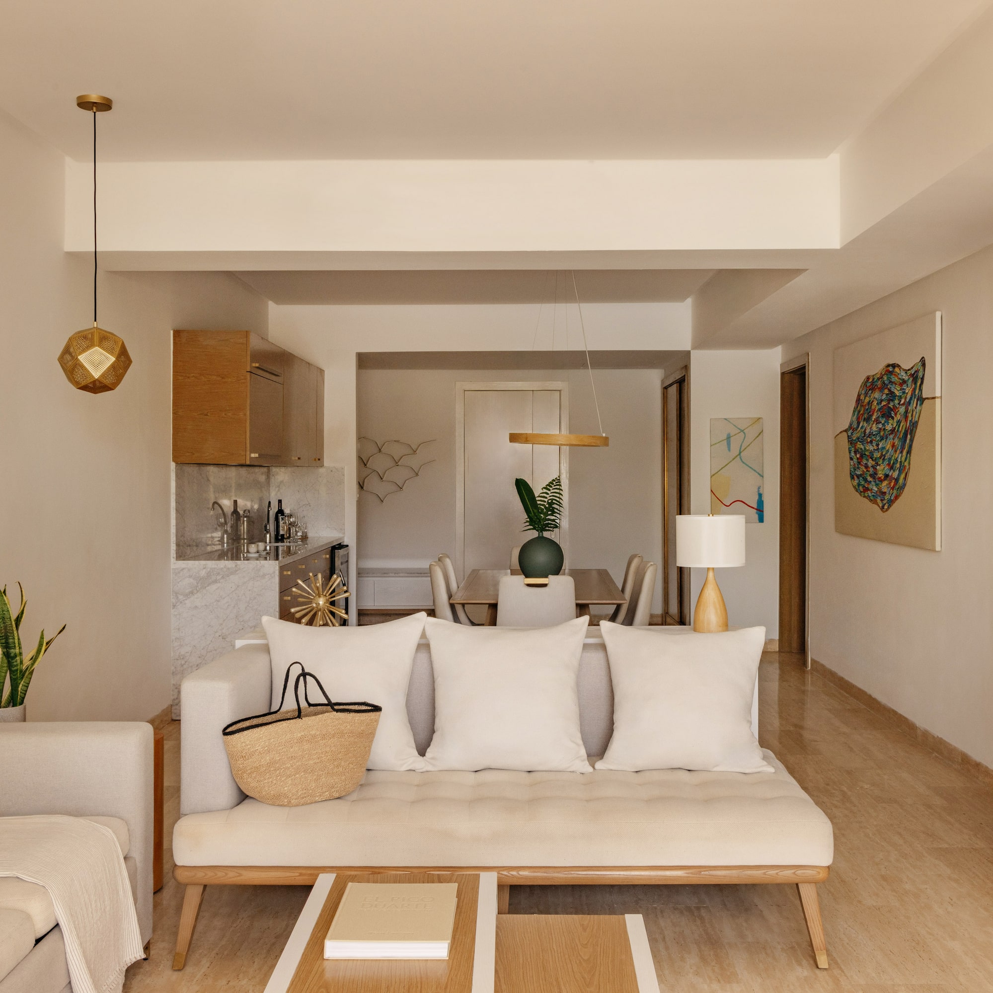 Open-concept living and dining room with neutral modern decor, cream sofa.