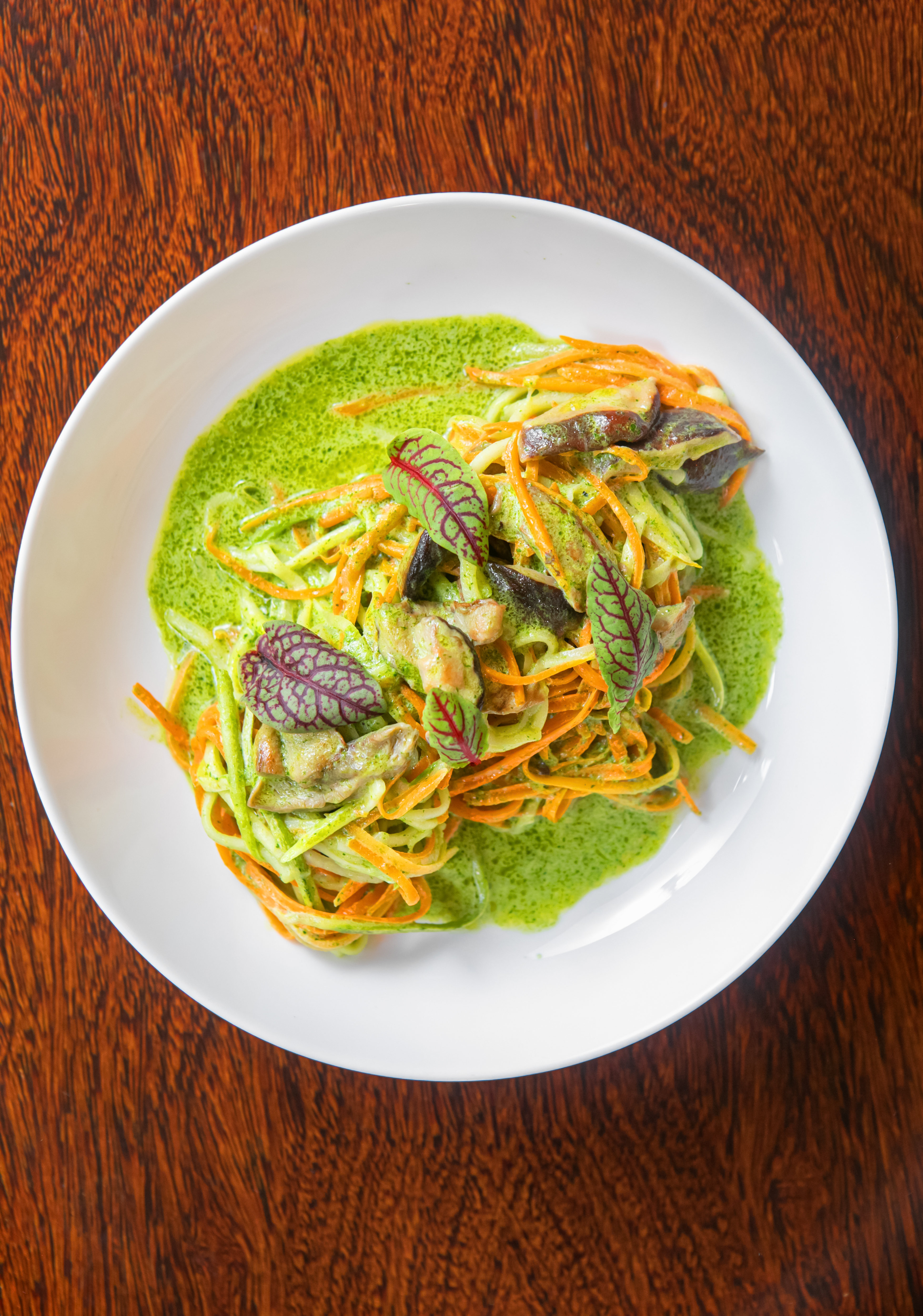 Colorful spiralized vegetable pasta with green sauce, mushrooms & microgreens.