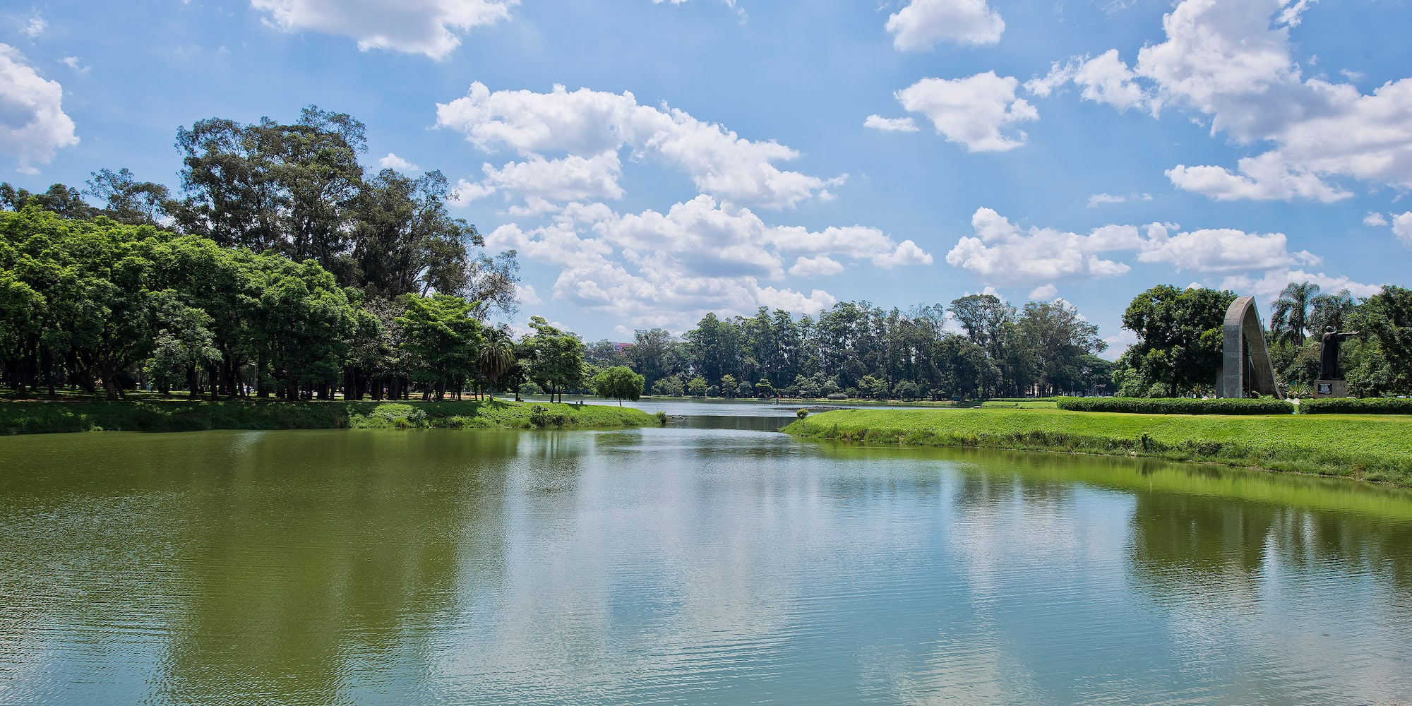 a body of water with trees and grass around it