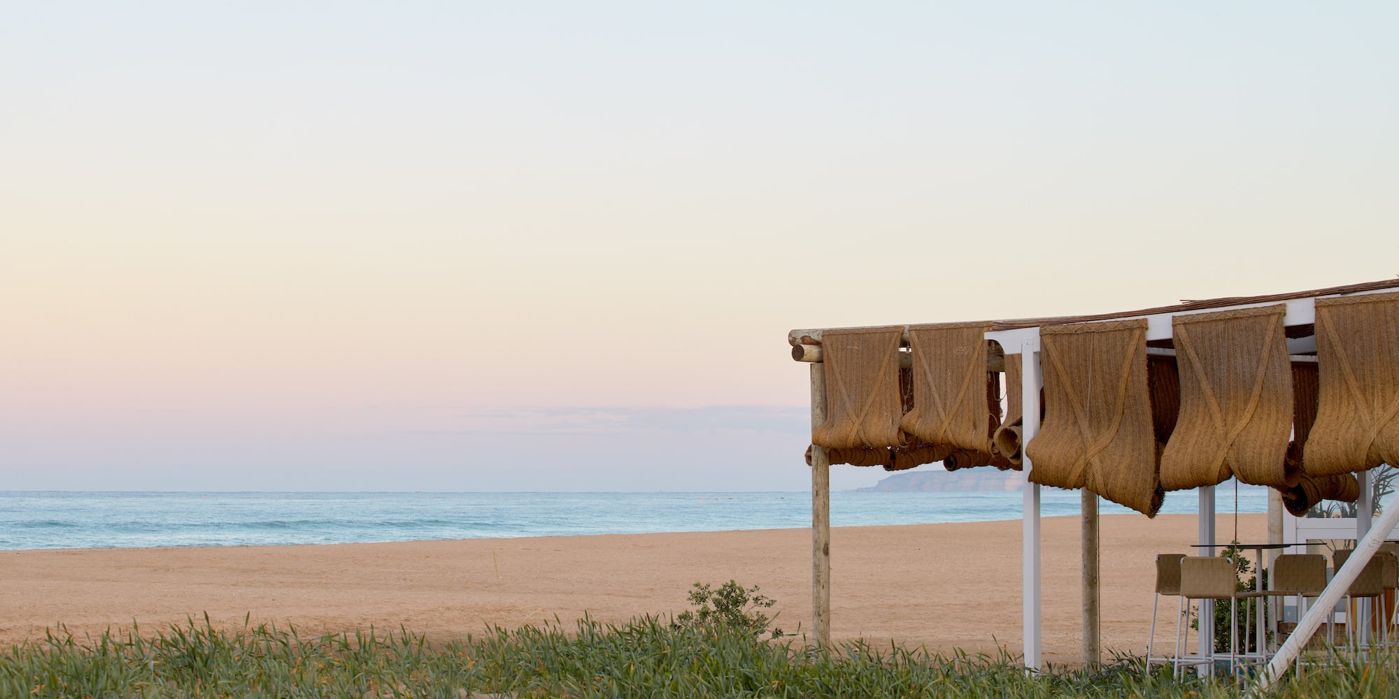 a beach with a few chairs and a body of water