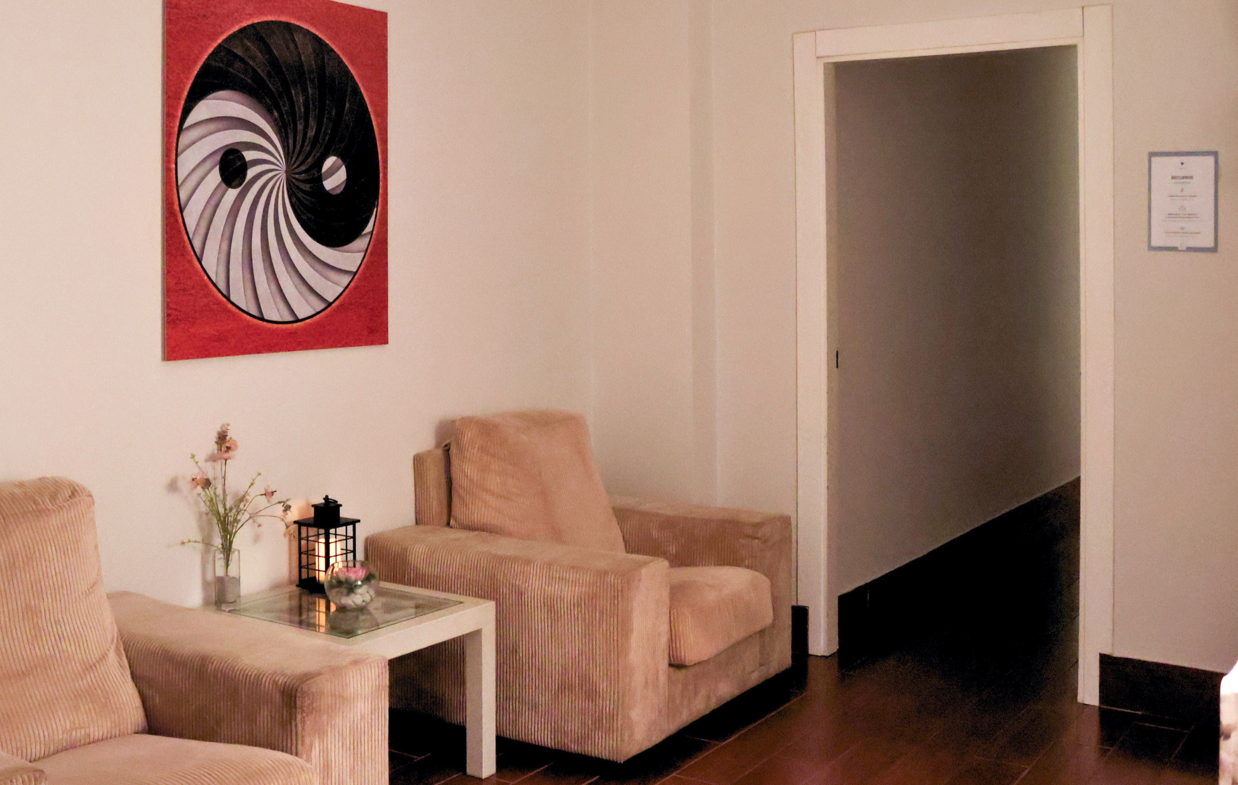 Cozy relaxation room with beige armchairs, side table, and yin-yang wall art.