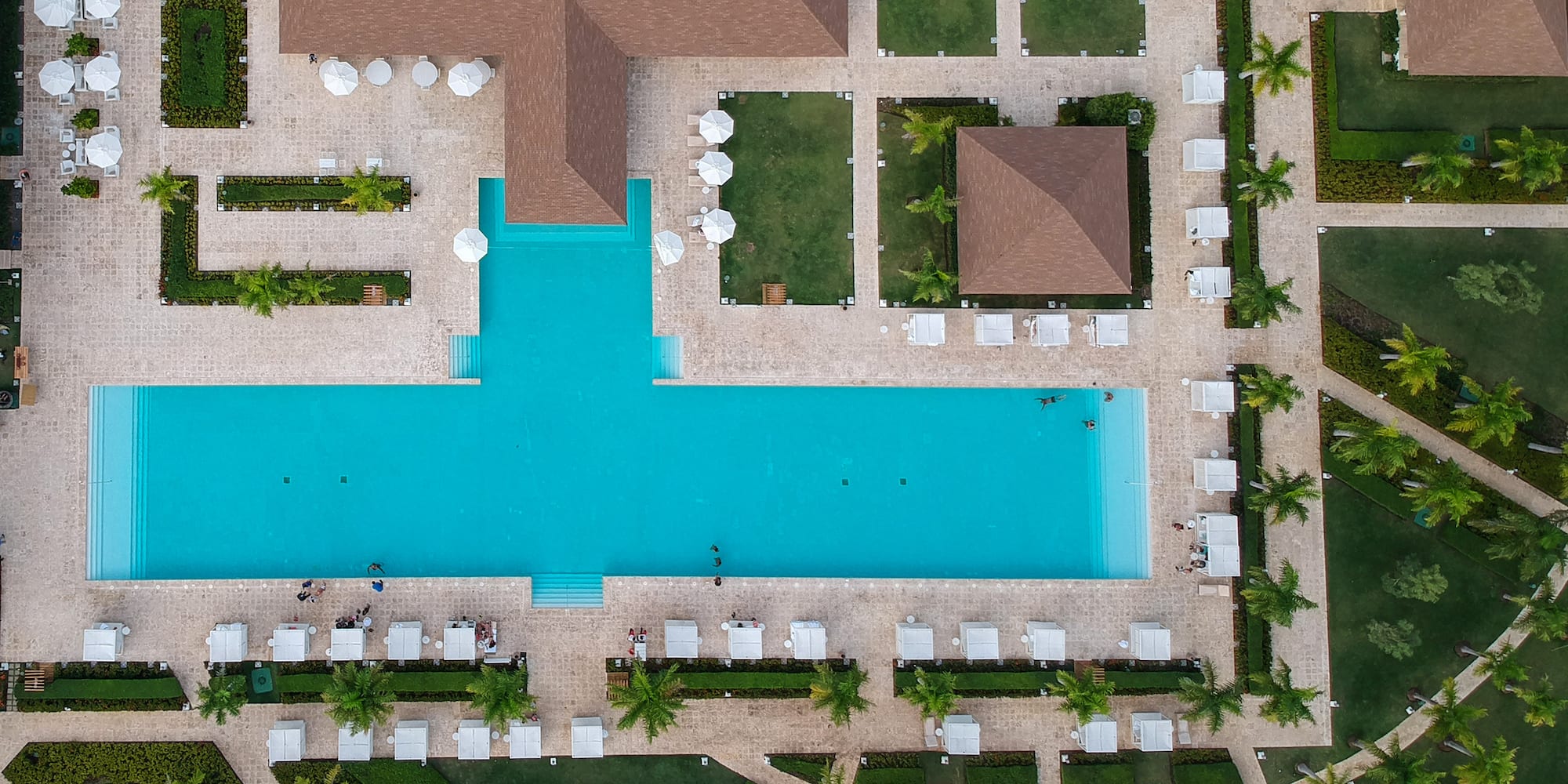 a pool surrounded by green grass and trees