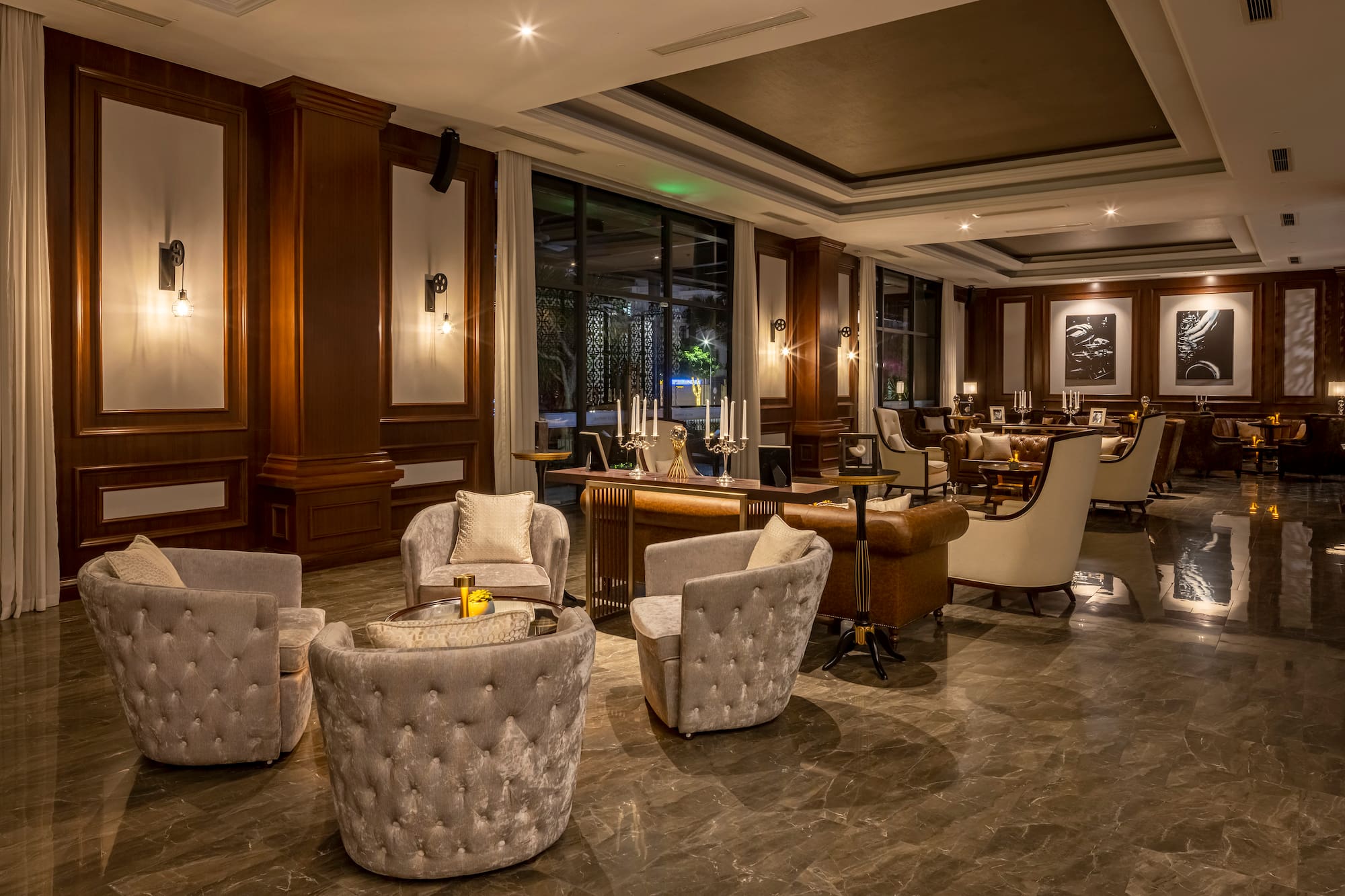 Elegant hotel lounge with plush seating, wood paneling, marble floor, and warm lighting.