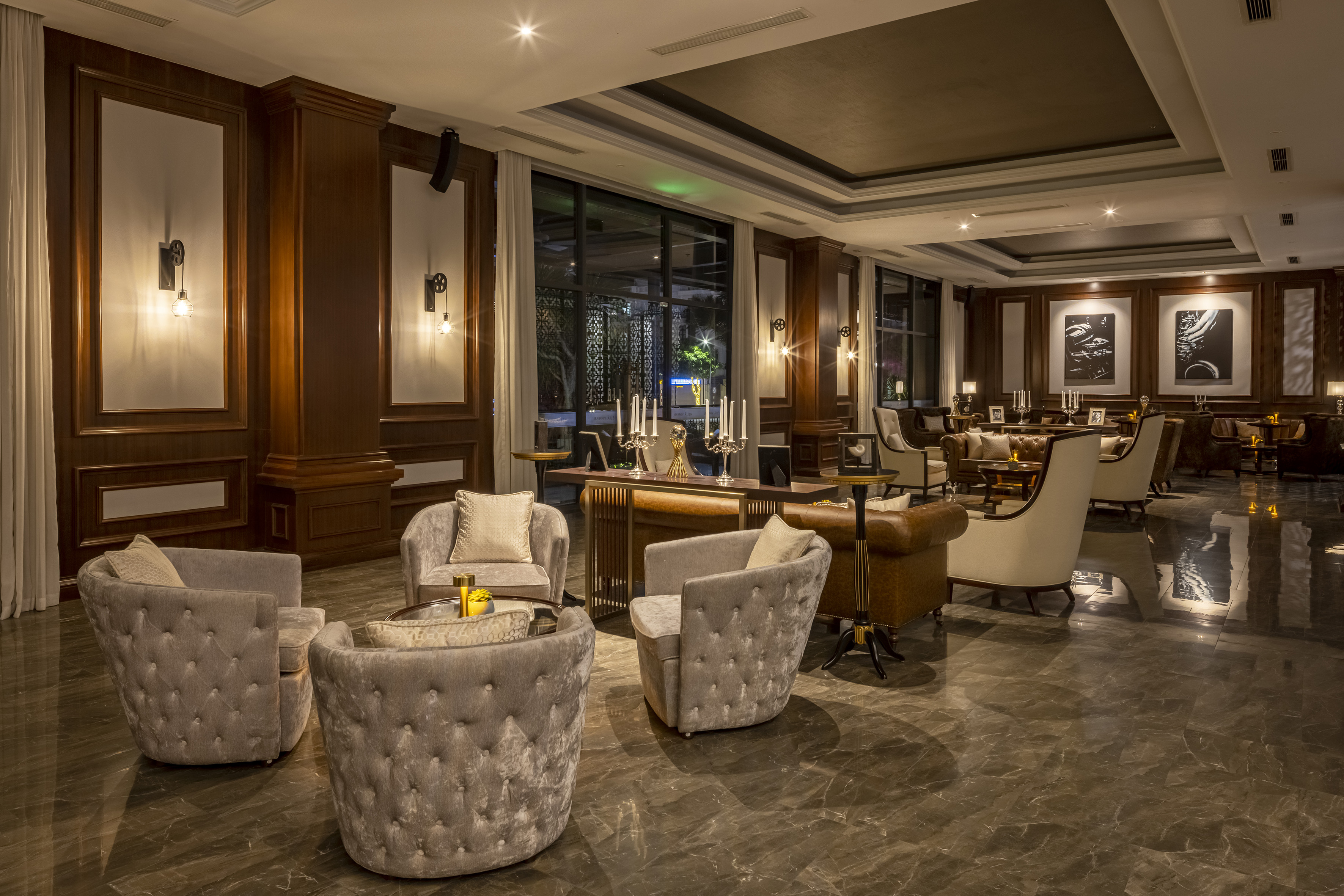 Elegant hotel lounge with plush seating, wood paneling, marble floor, and warm lighting.