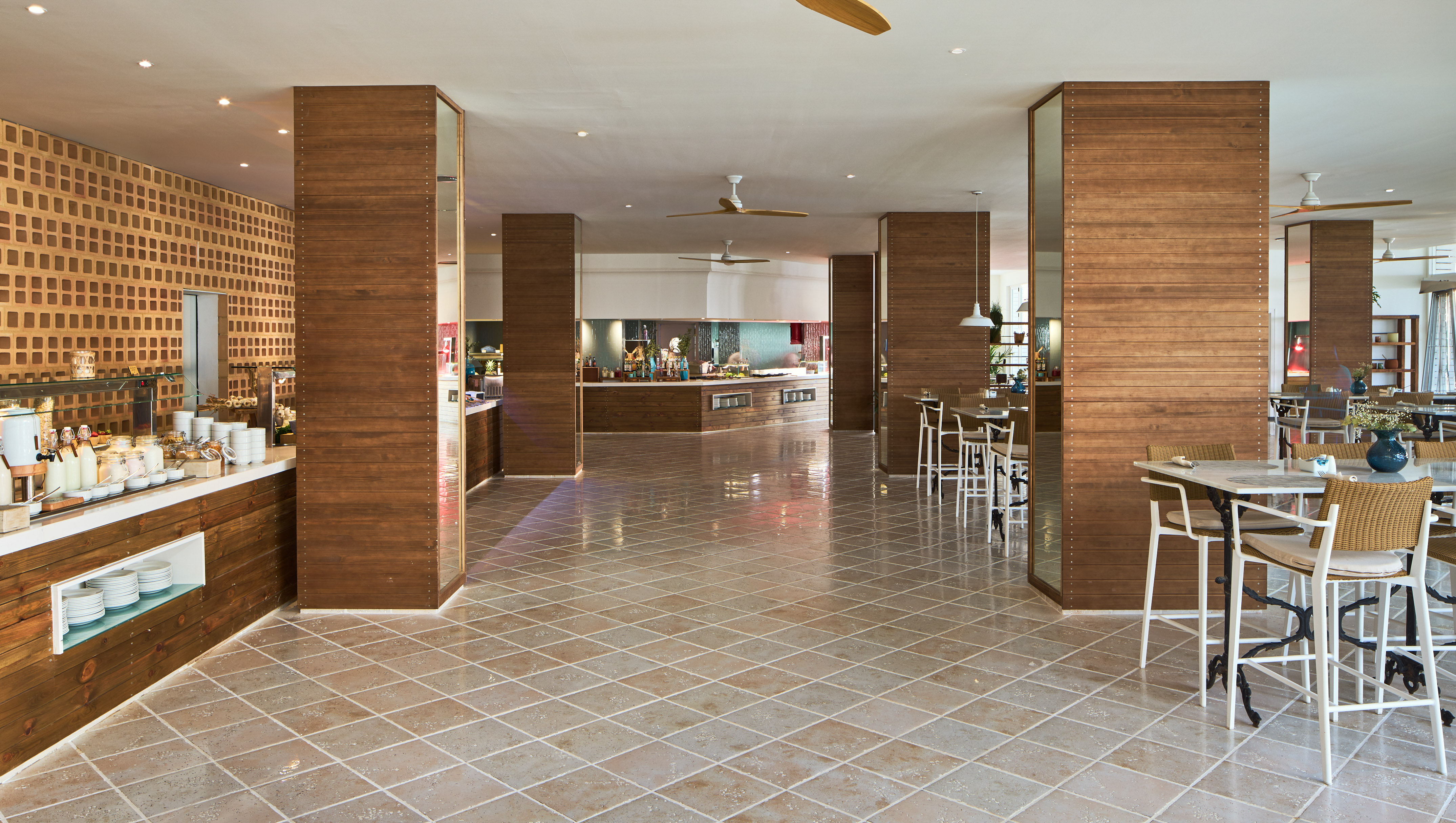 Spacious resort dining area with buffet stations and modern wooden decor.