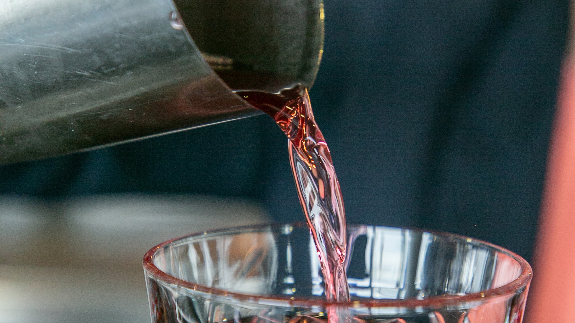a person pouring a drink into a glass