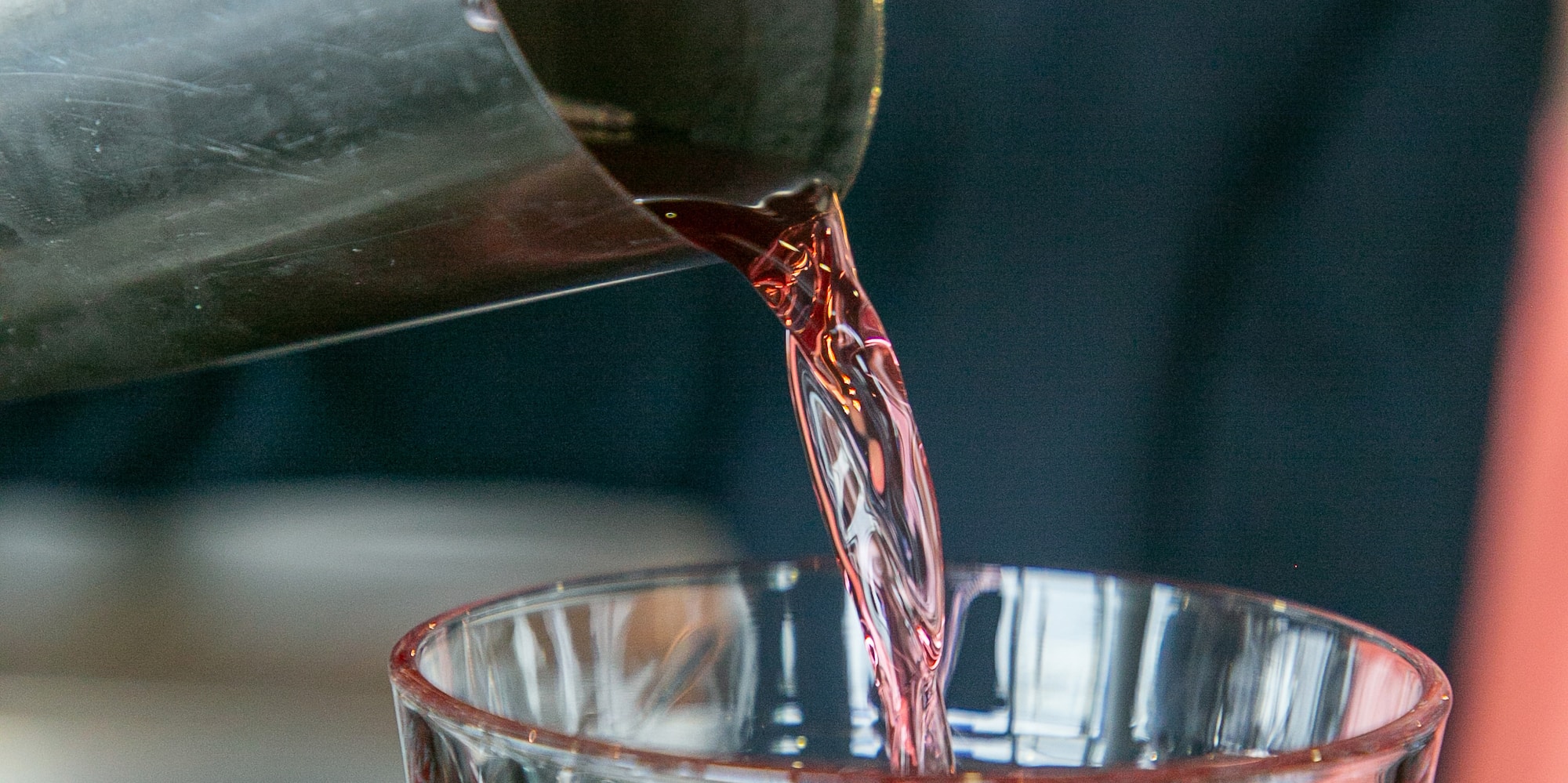 a person pouring a drink into a glass
