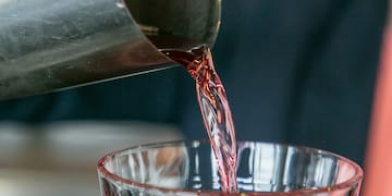 a person pouring a drink into a glass