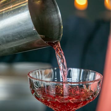 a person pouring a drink into a glass