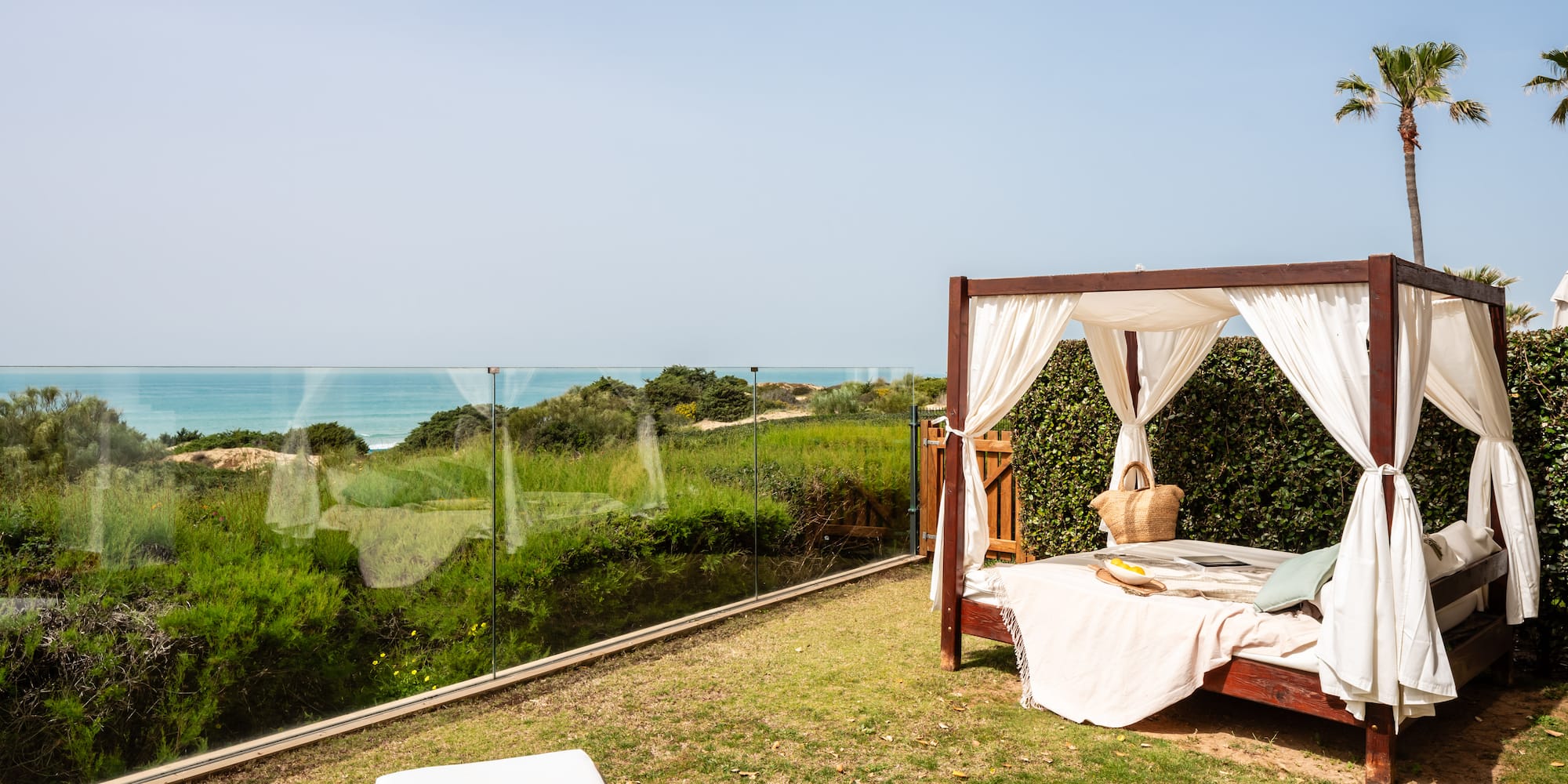a bed on a lawn with a view of the ocean