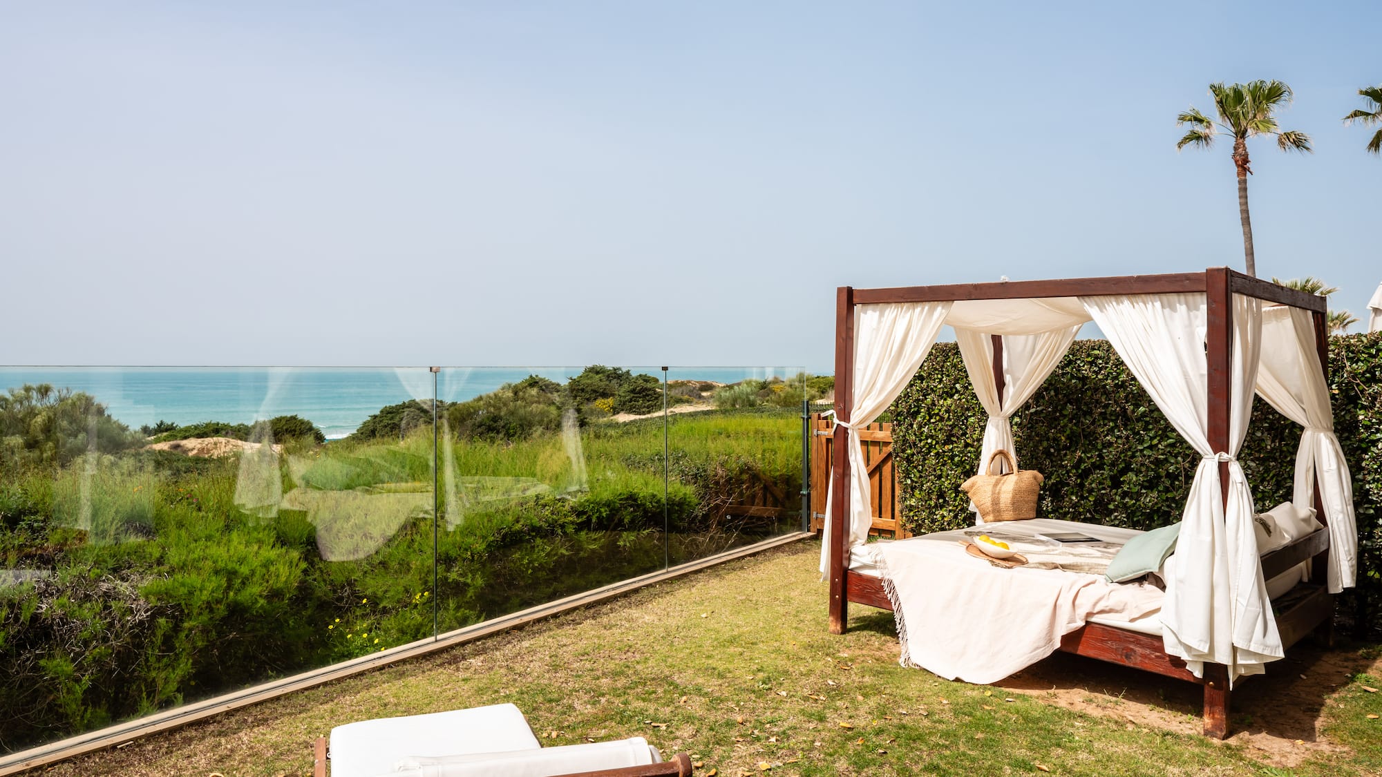 a bed on a lawn with a view of the ocean