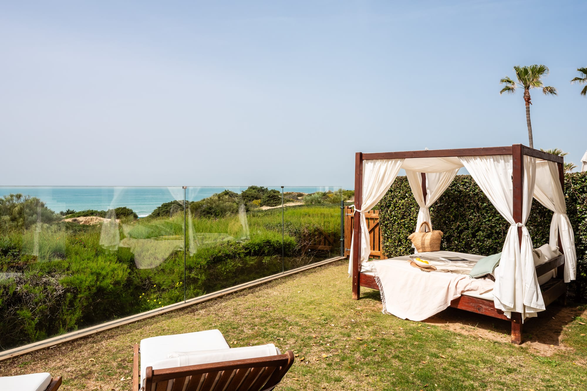 a bed on a lawn with a view of the ocean