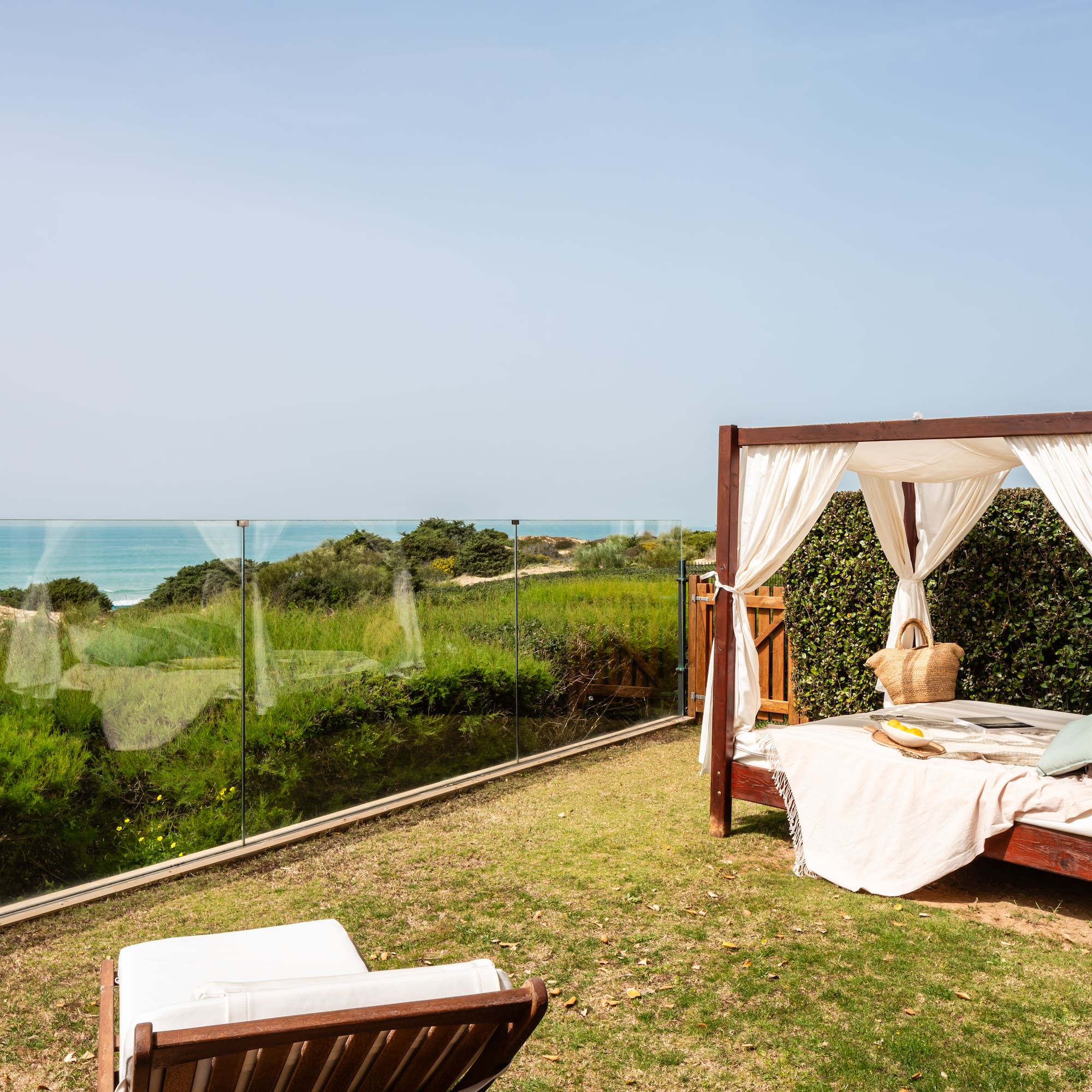 a bed on a lawn with a view of the ocean