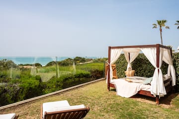 a bed on a lawn with a view of the ocean
