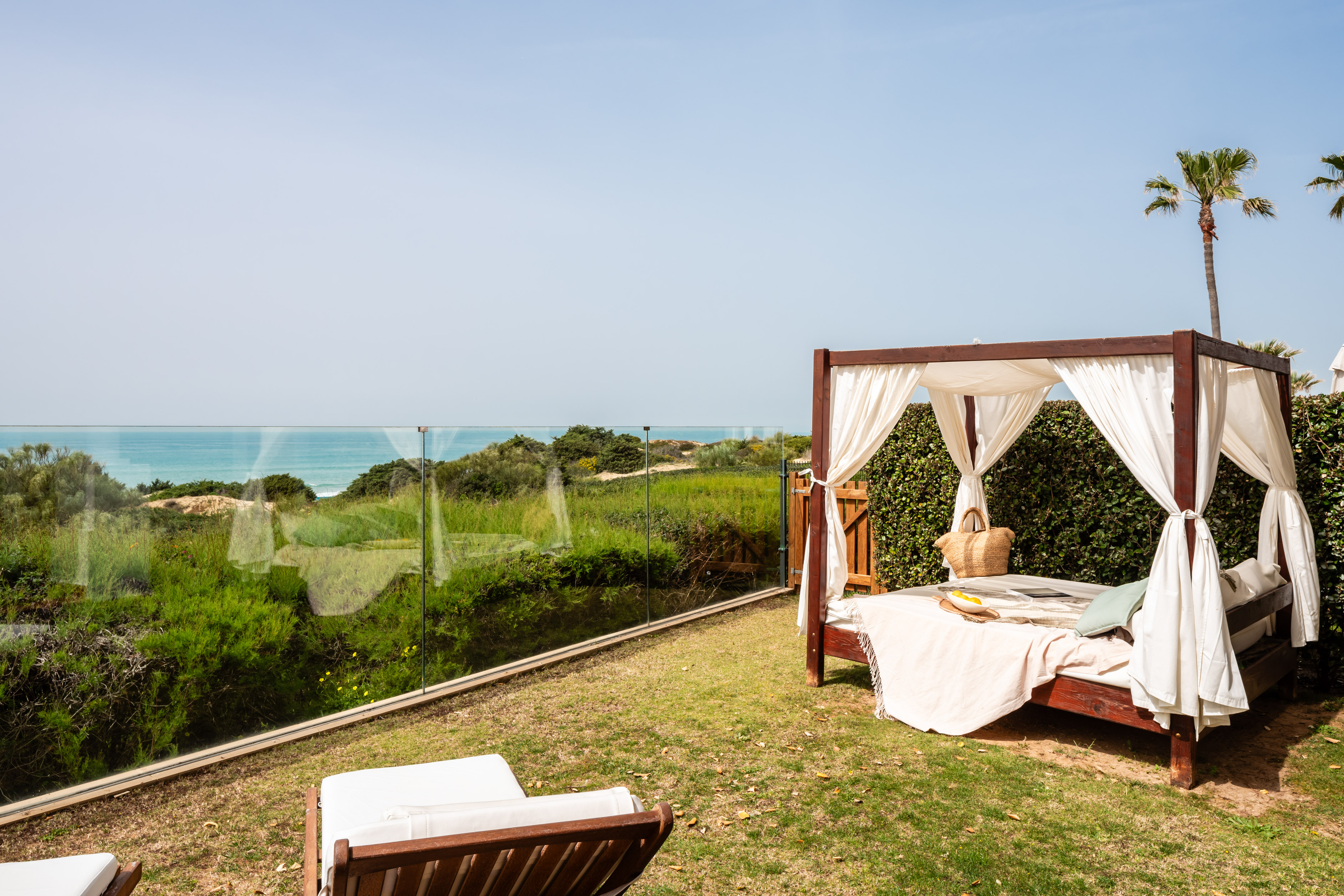 a bed on a lawn with a view of the ocean