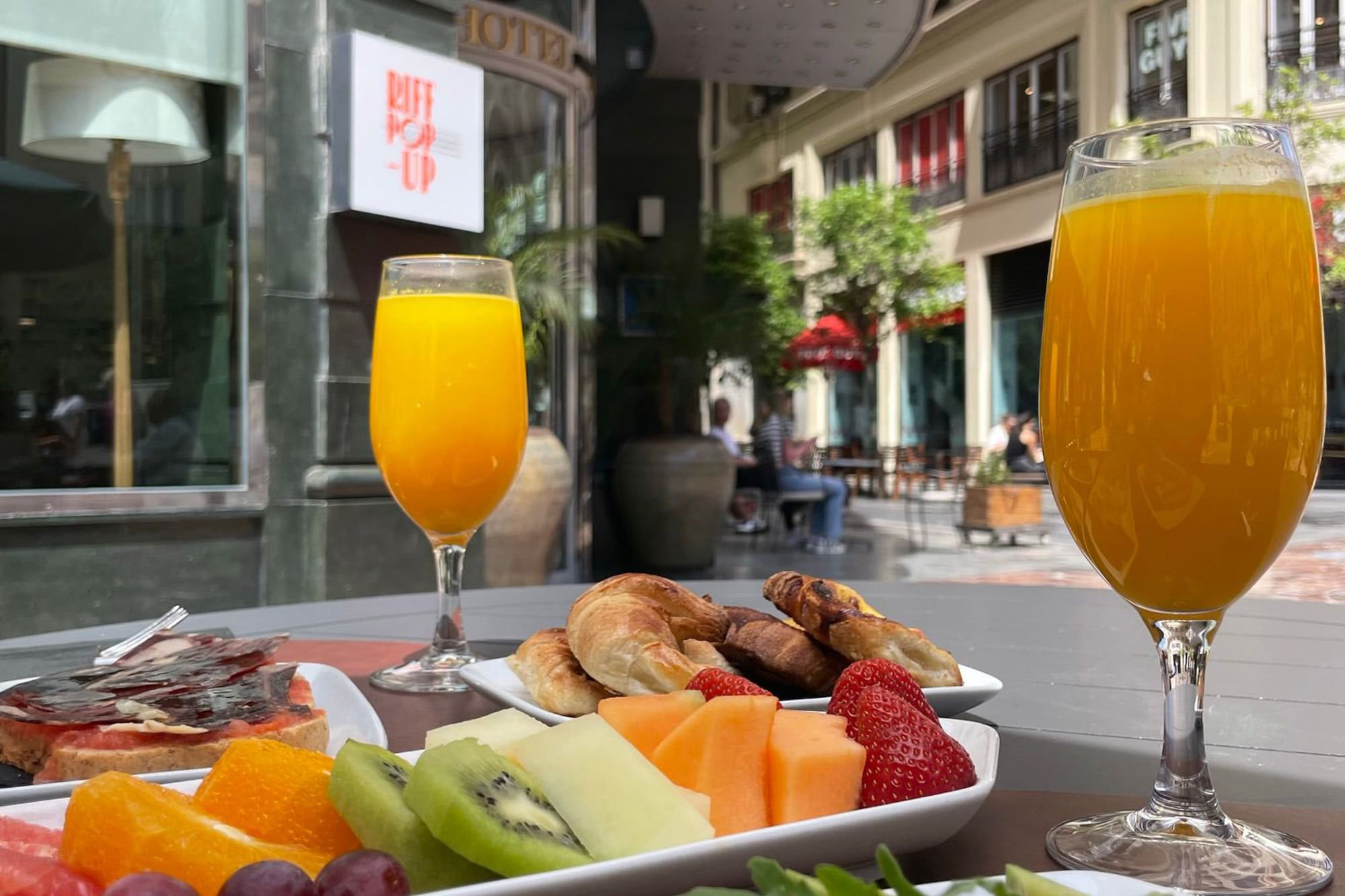 Hotel breakfast with fresh fruit, croissants, salmon toast, and orange juice.