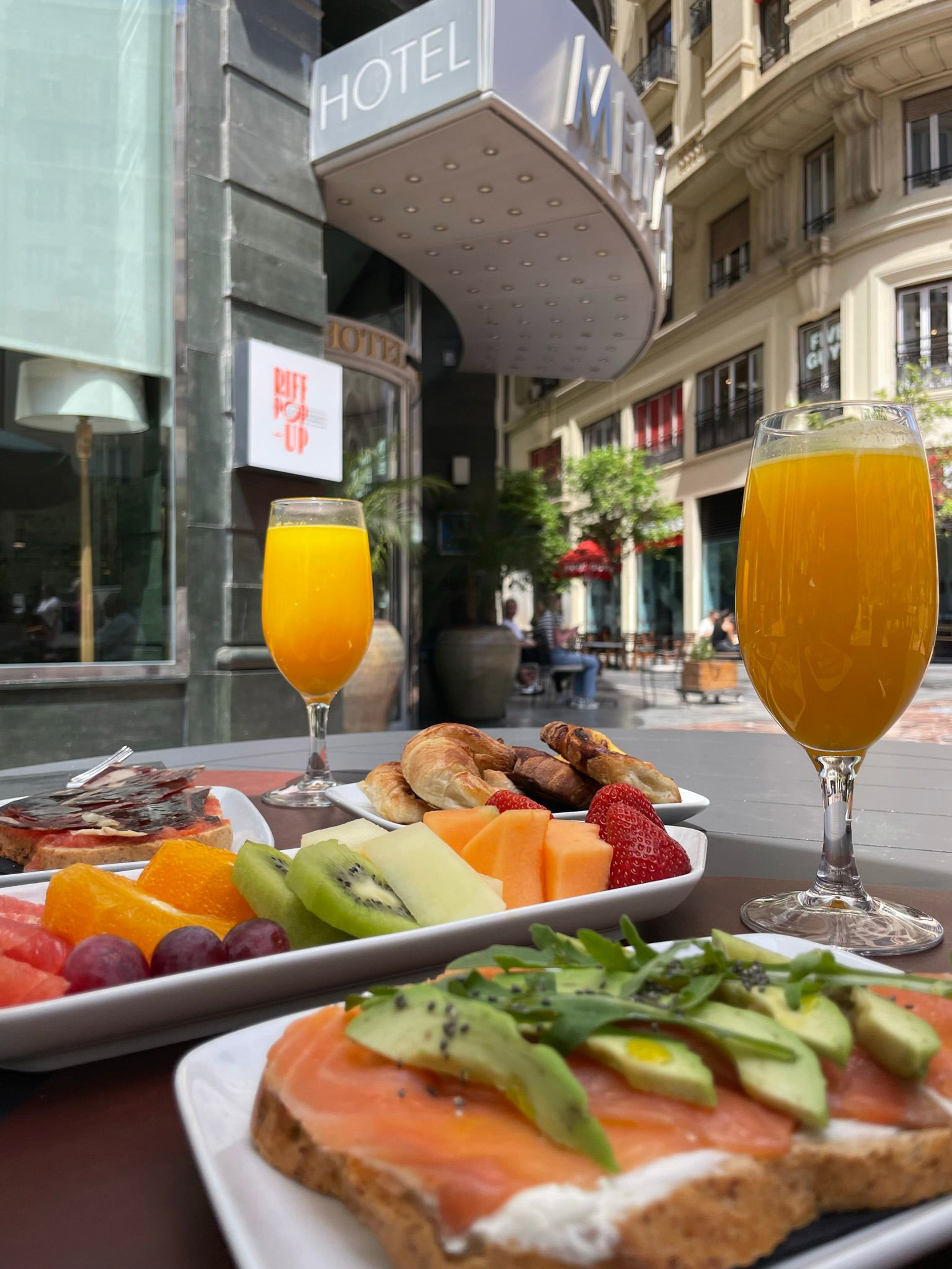 Hotel breakfast with fresh fruit, croissants, salmon toast, and orange juice.