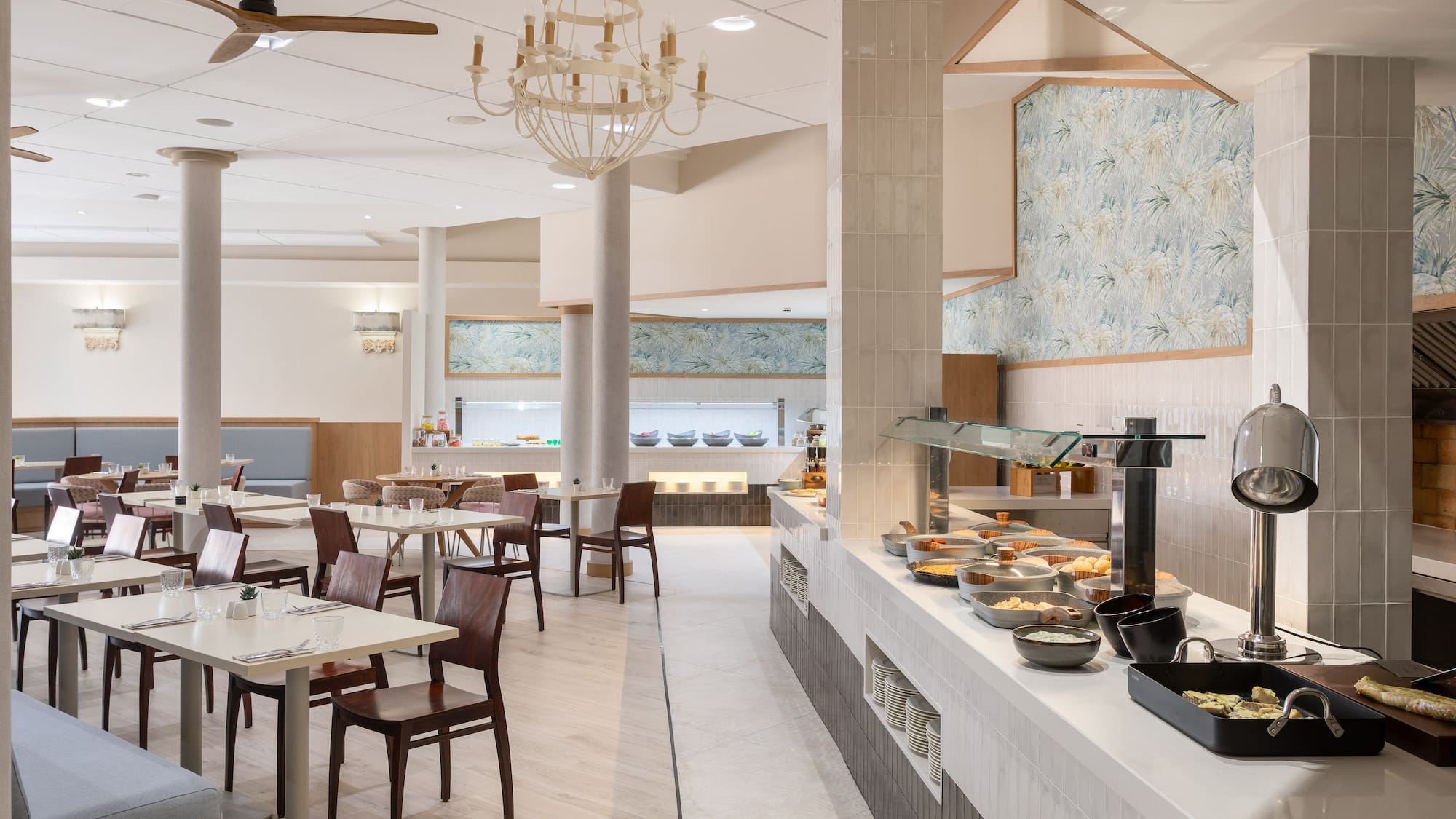 Modern hotel restaurant with a buffet, dining tables, and seating area.
