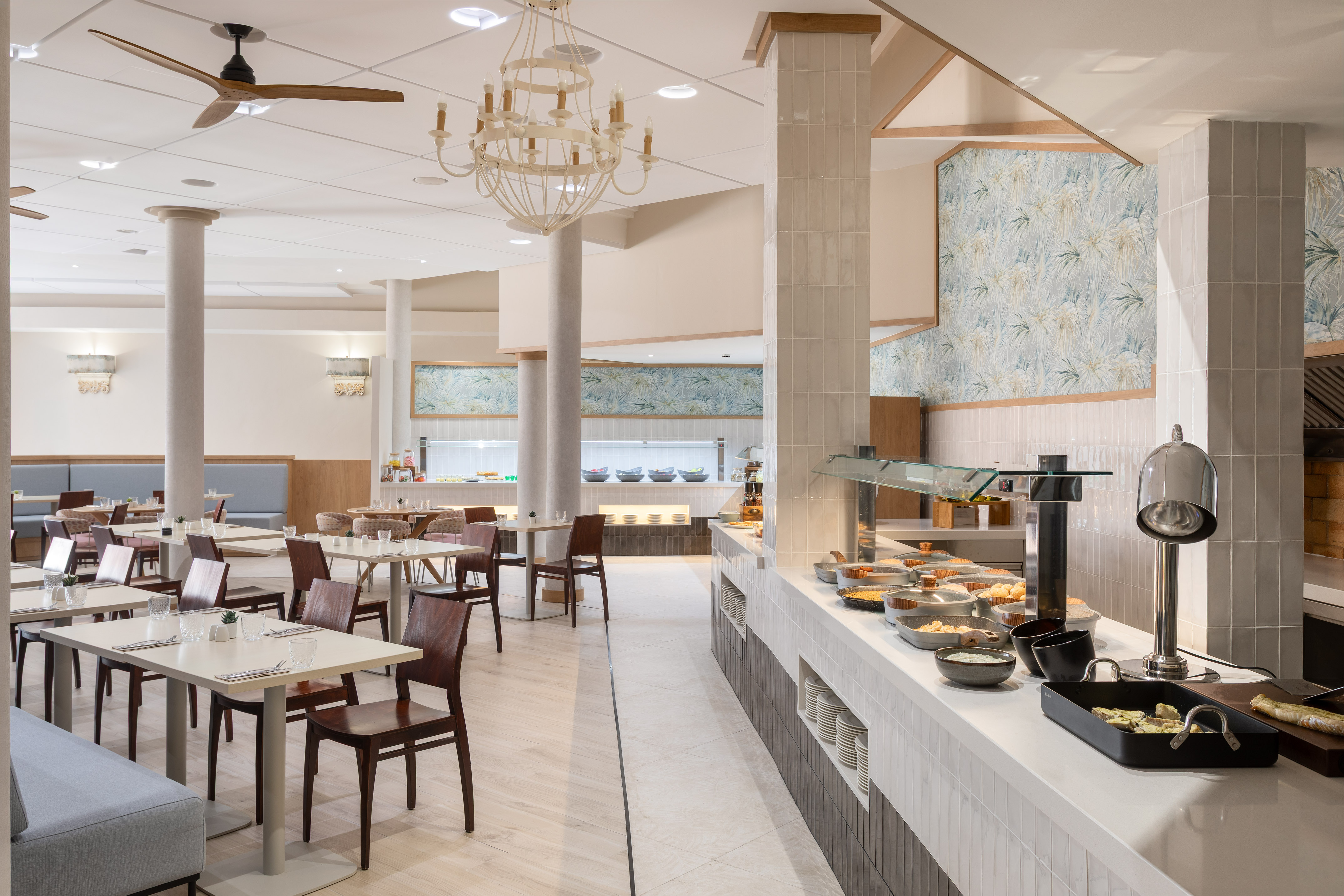 Hotel dining room with breakfast buffet, modern decor, and tables.