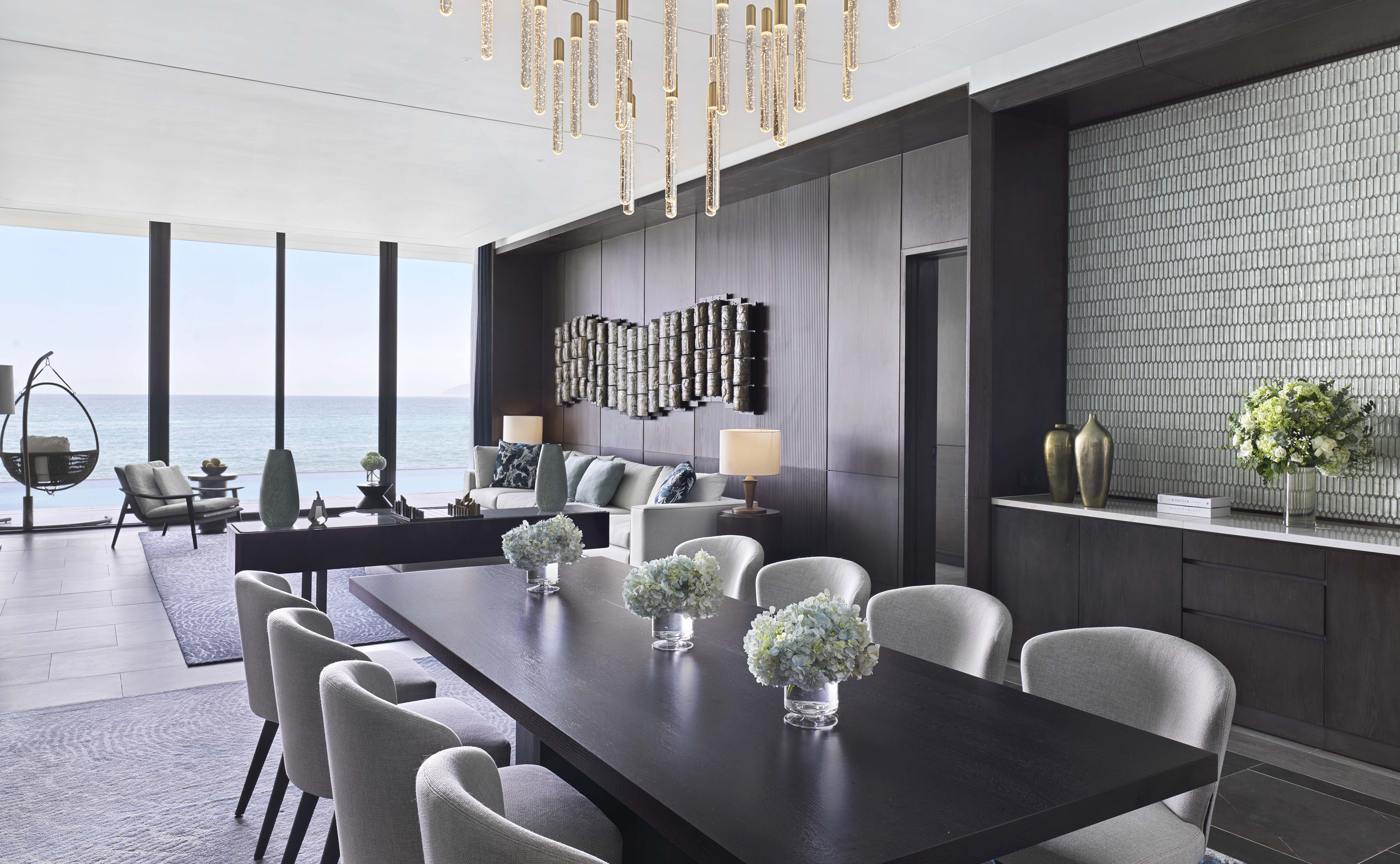 Luxury ocean view living and dining room with modern furniture and chandelier.