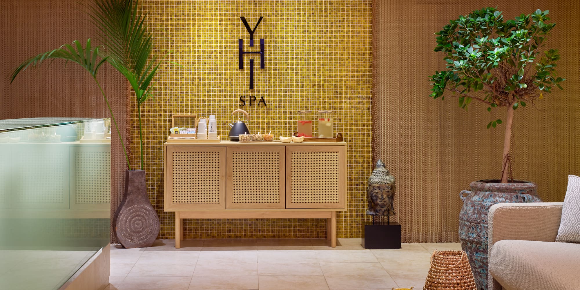 a room with a yellow tile wall and a cabinet with a potted plant