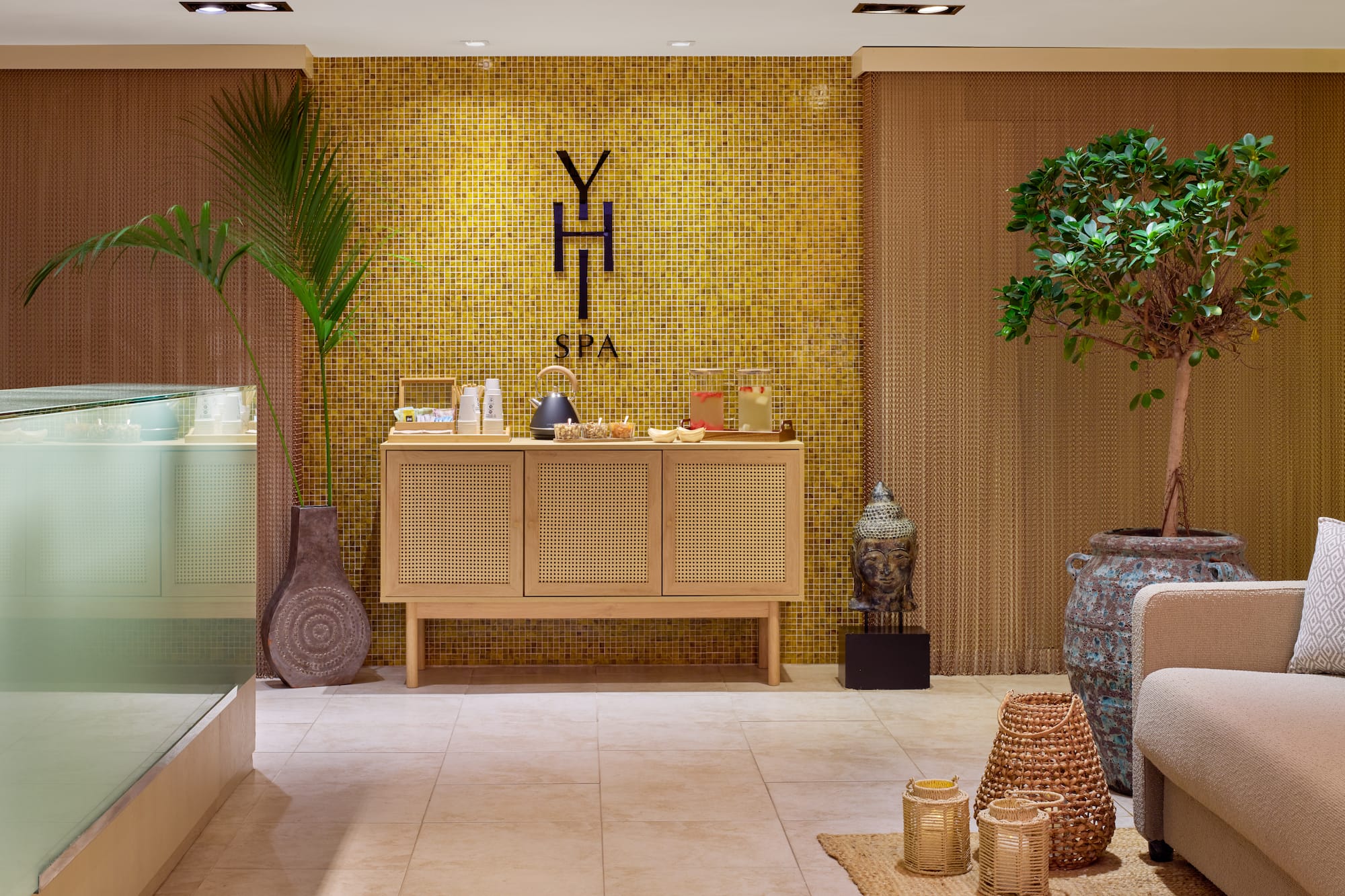a room with a yellow tile wall and a cabinet with a potted plant