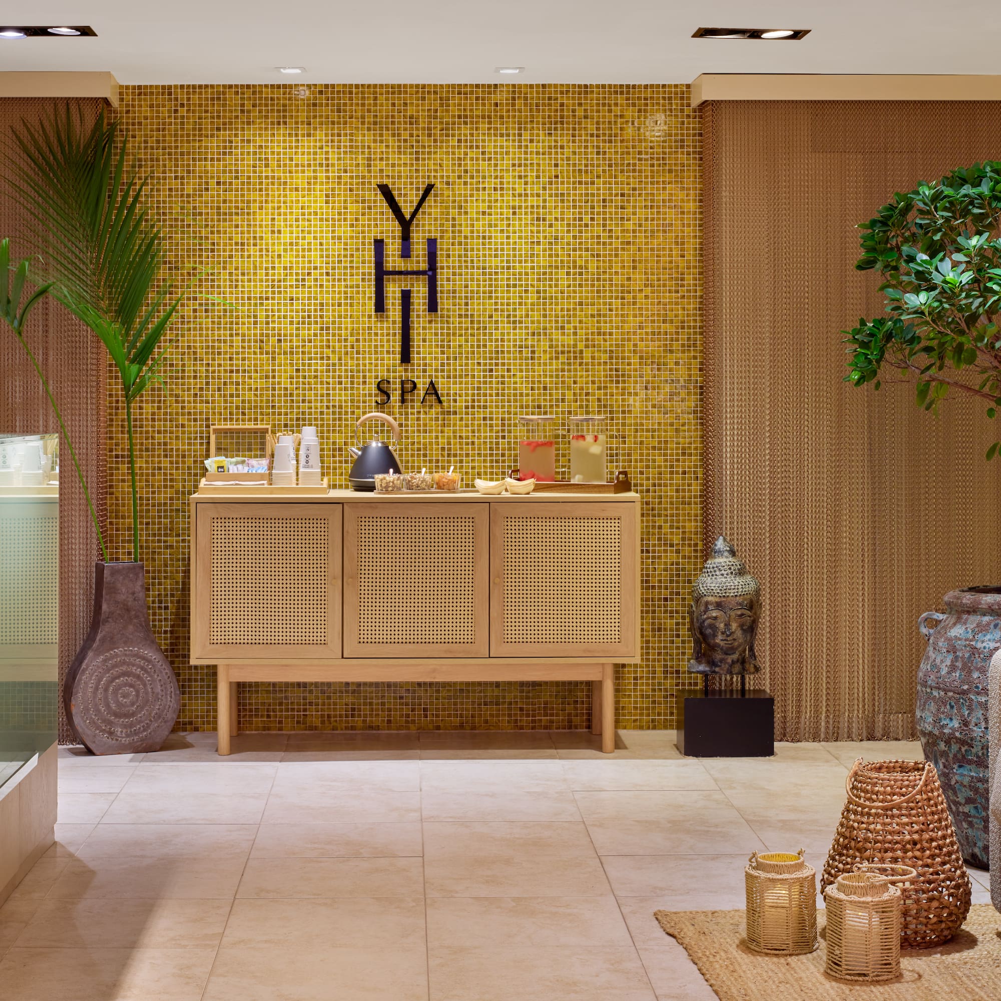 a room with a yellow tile wall and a cabinet with a potted plant