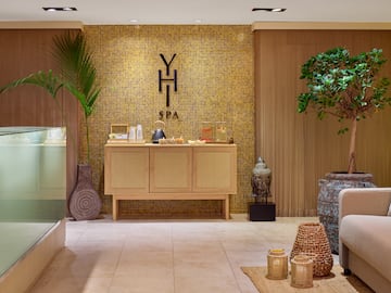 a room with a yellow tile wall and a cabinet with a potted plant