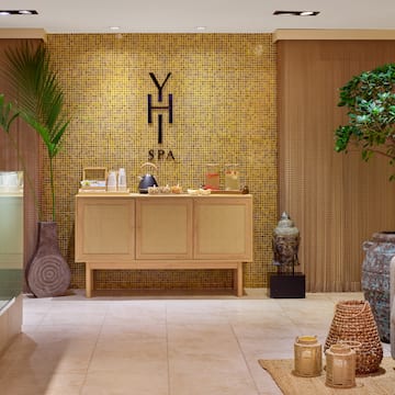 a room with a yellow tile wall and a cabinet with a potted plant