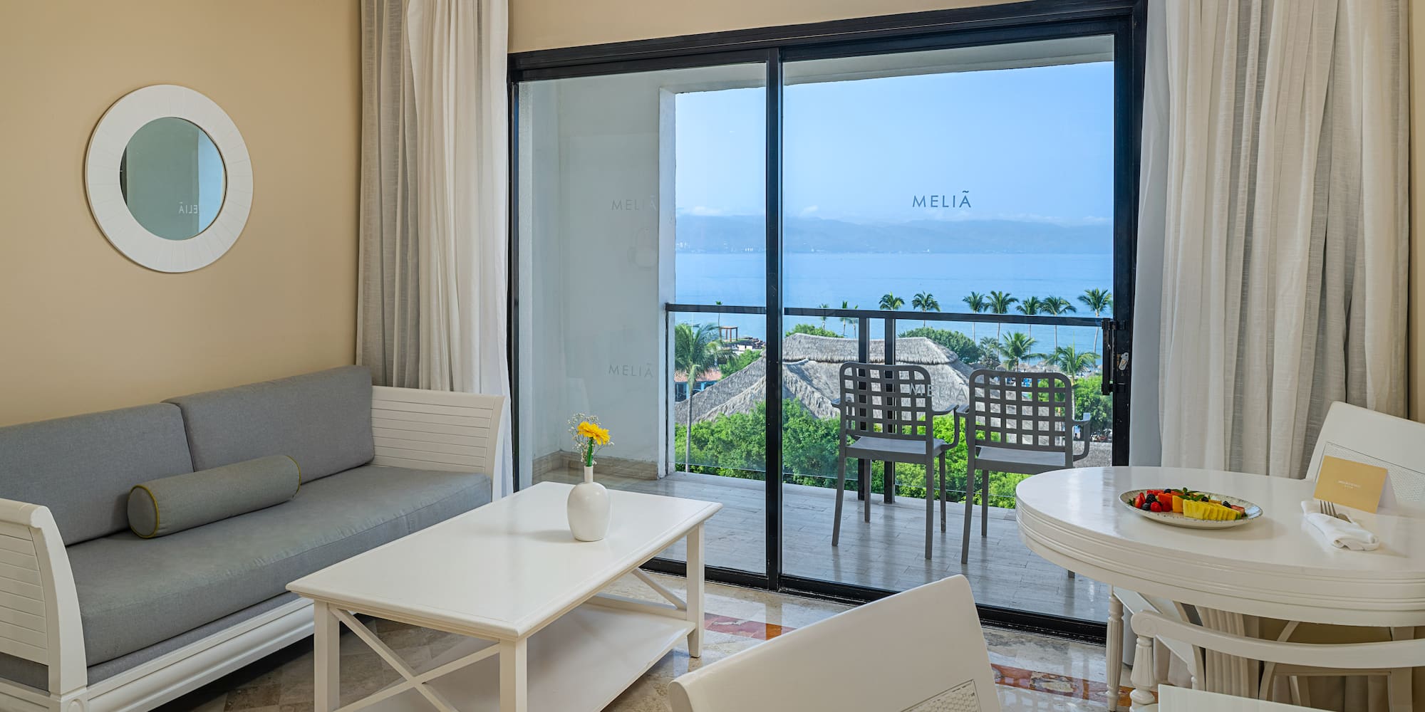 Hotel suite with ocean view balcony, living and dining areas.