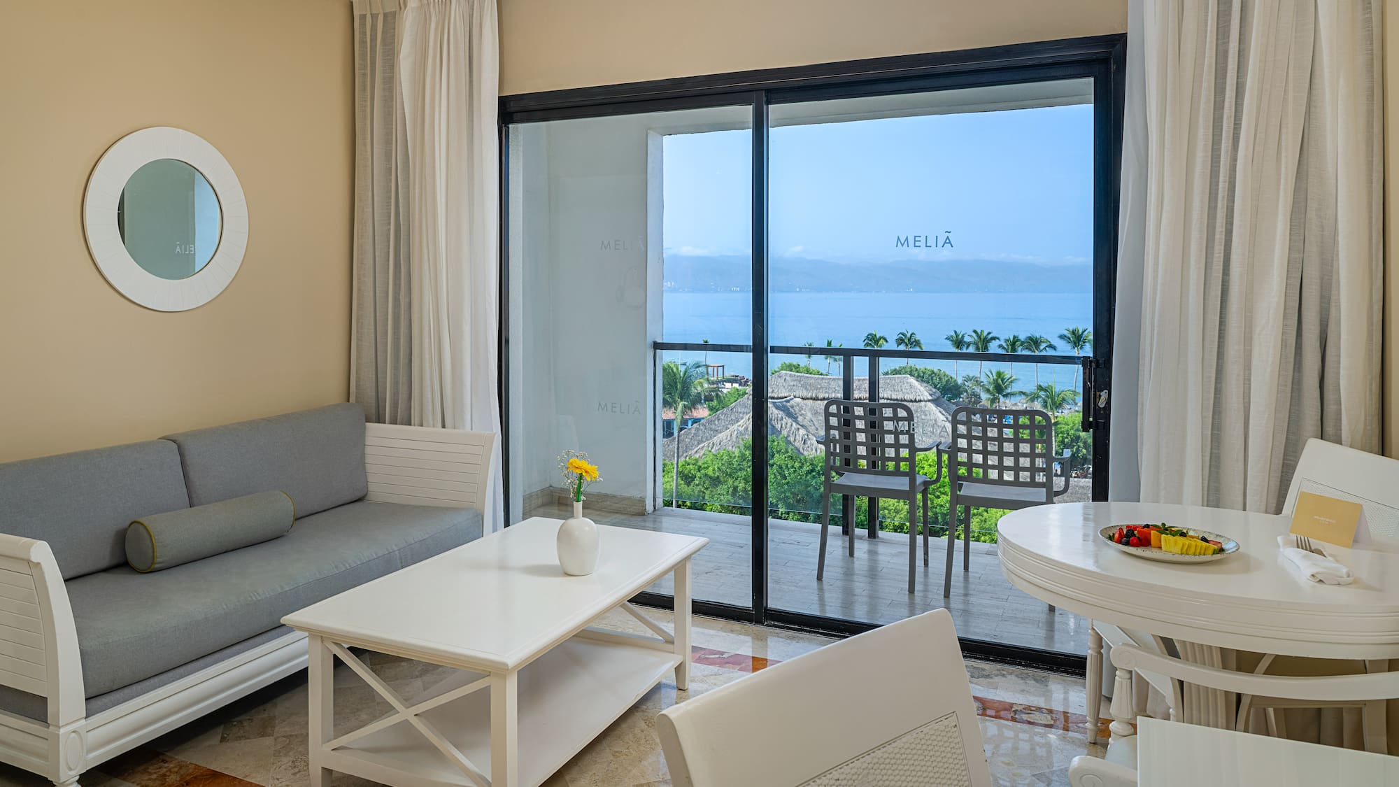 Hotel suite with ocean view balcony, living and dining areas.