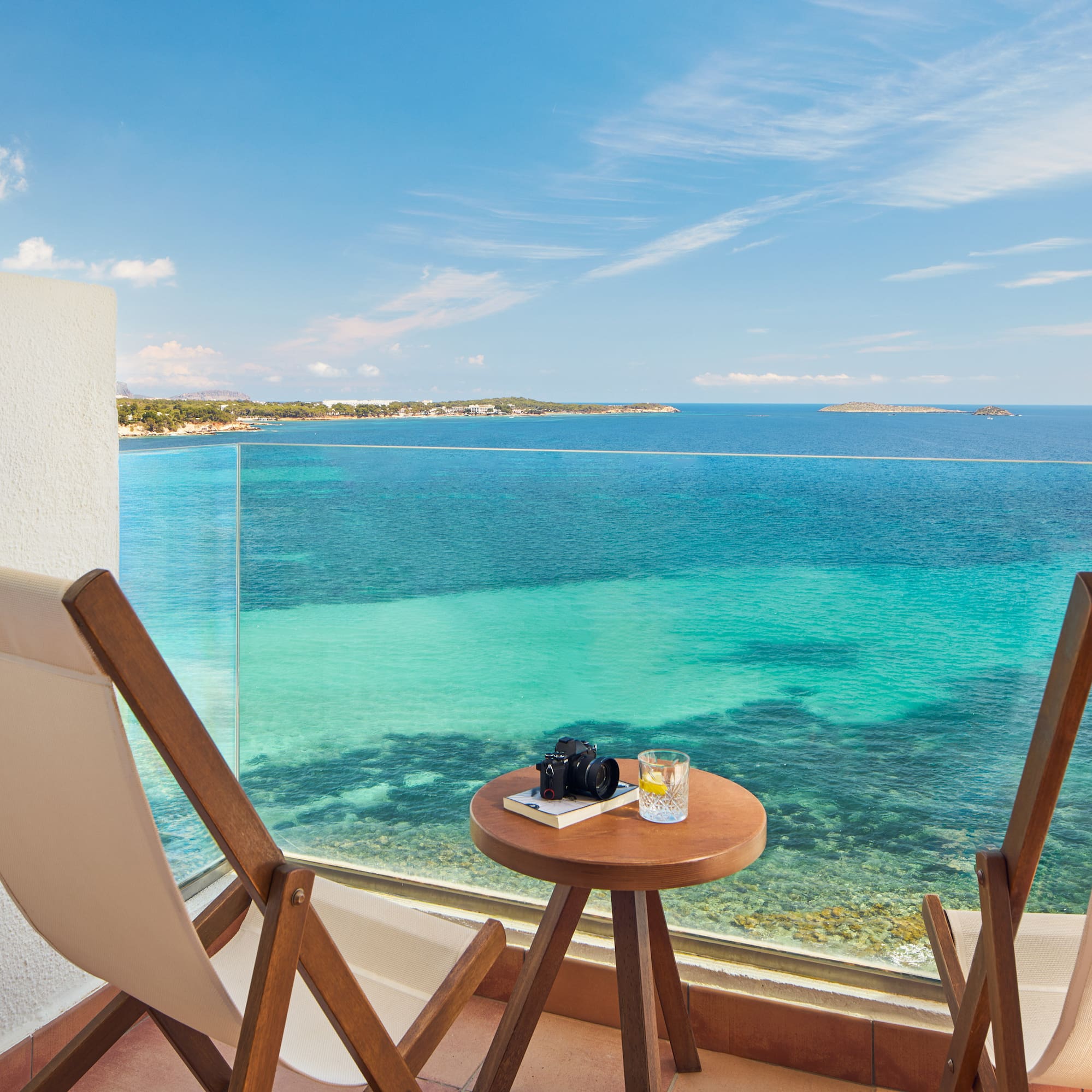a table and chairs on a balcony overlooking the ocean