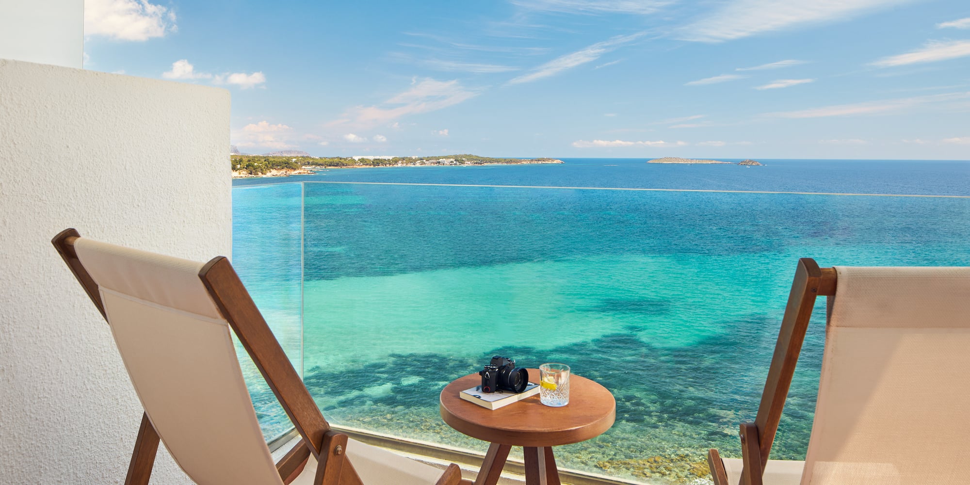 a table and chairs on a balcony overlooking the ocean