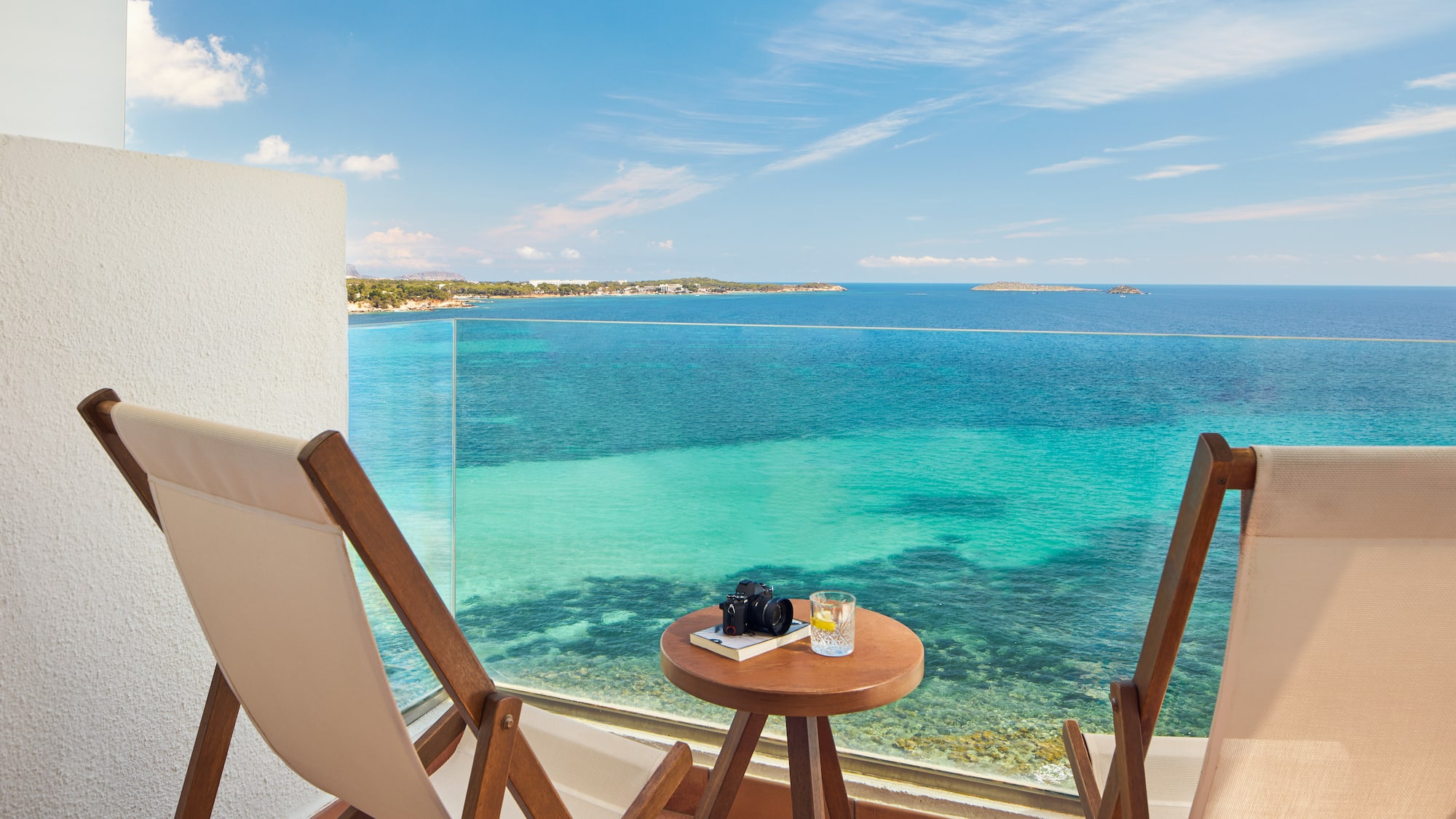 a table and chairs on a balcony overlooking the ocean
