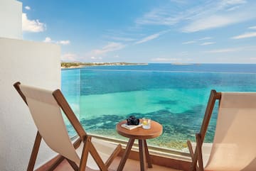 a table and chairs on a balcony overlooking the ocean