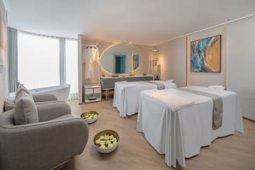 a room with white beds and a mirror