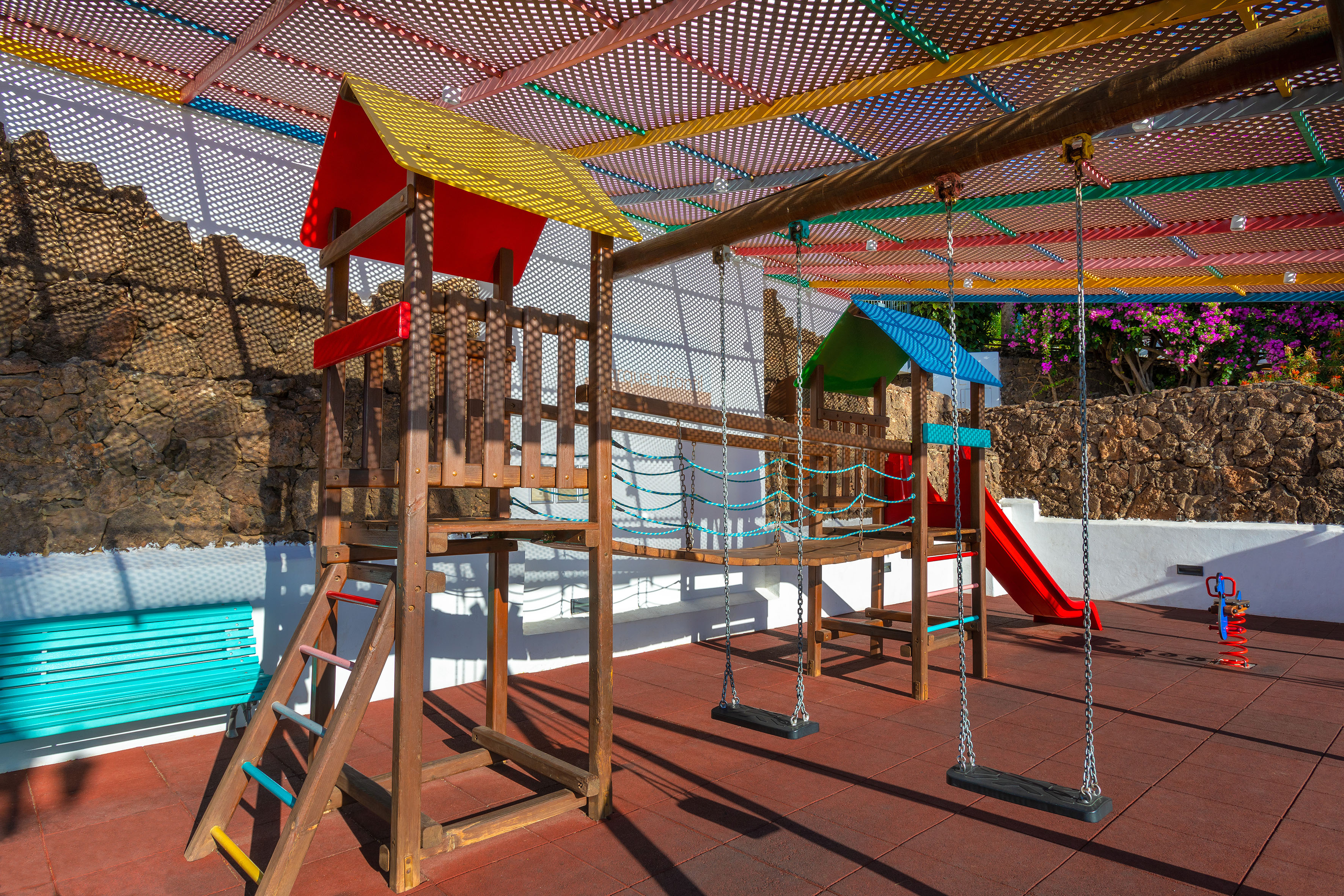 Vibrant wooden playground with swings, slide, and colorful canopy.