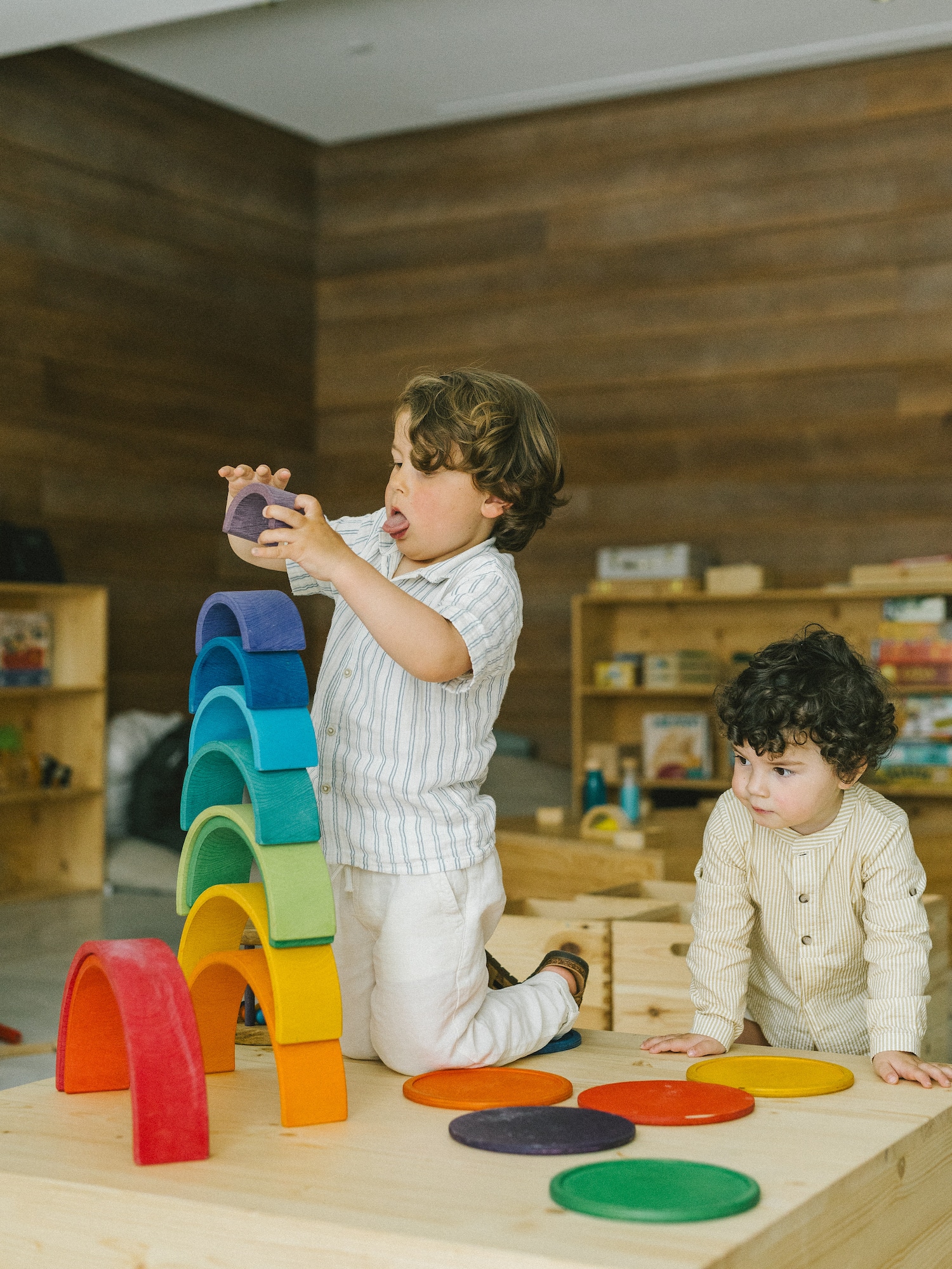 Niños jugando con arcoíris de bloques de madera, juego creativo.
