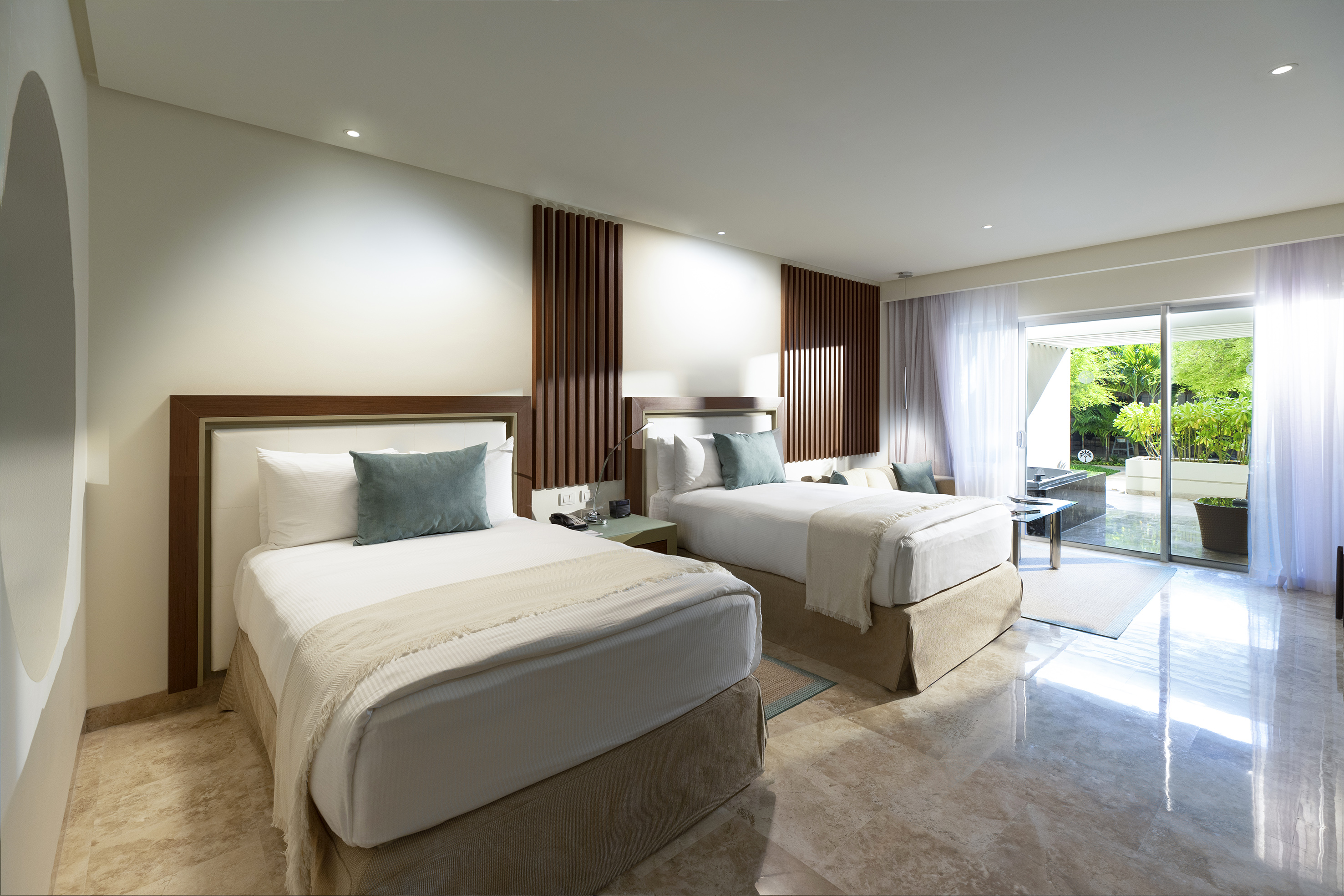Modern hotel room with two beds, wood decor, marble floor, and garden patio.