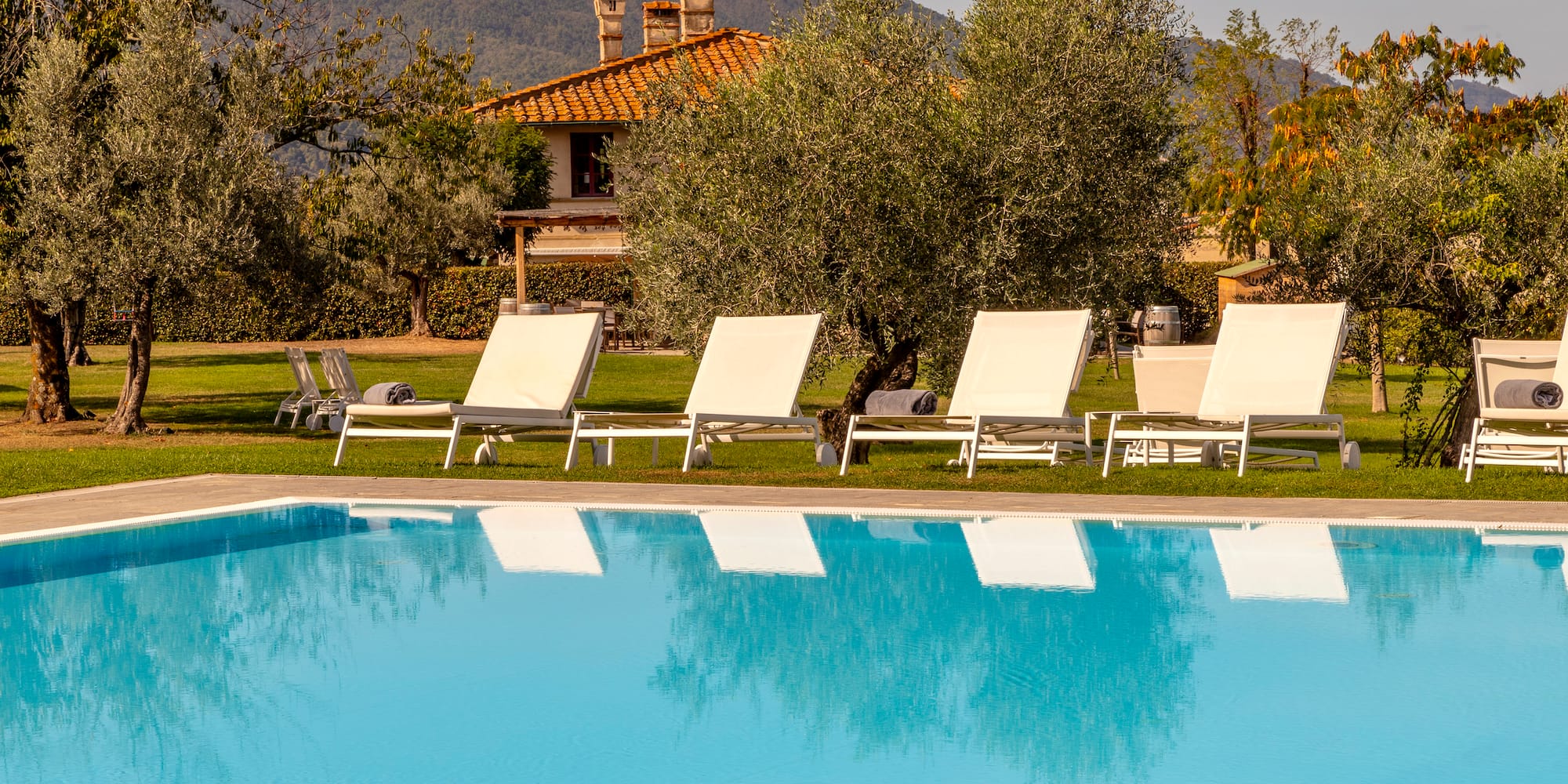 a pool with lounge chairs and trees in the background