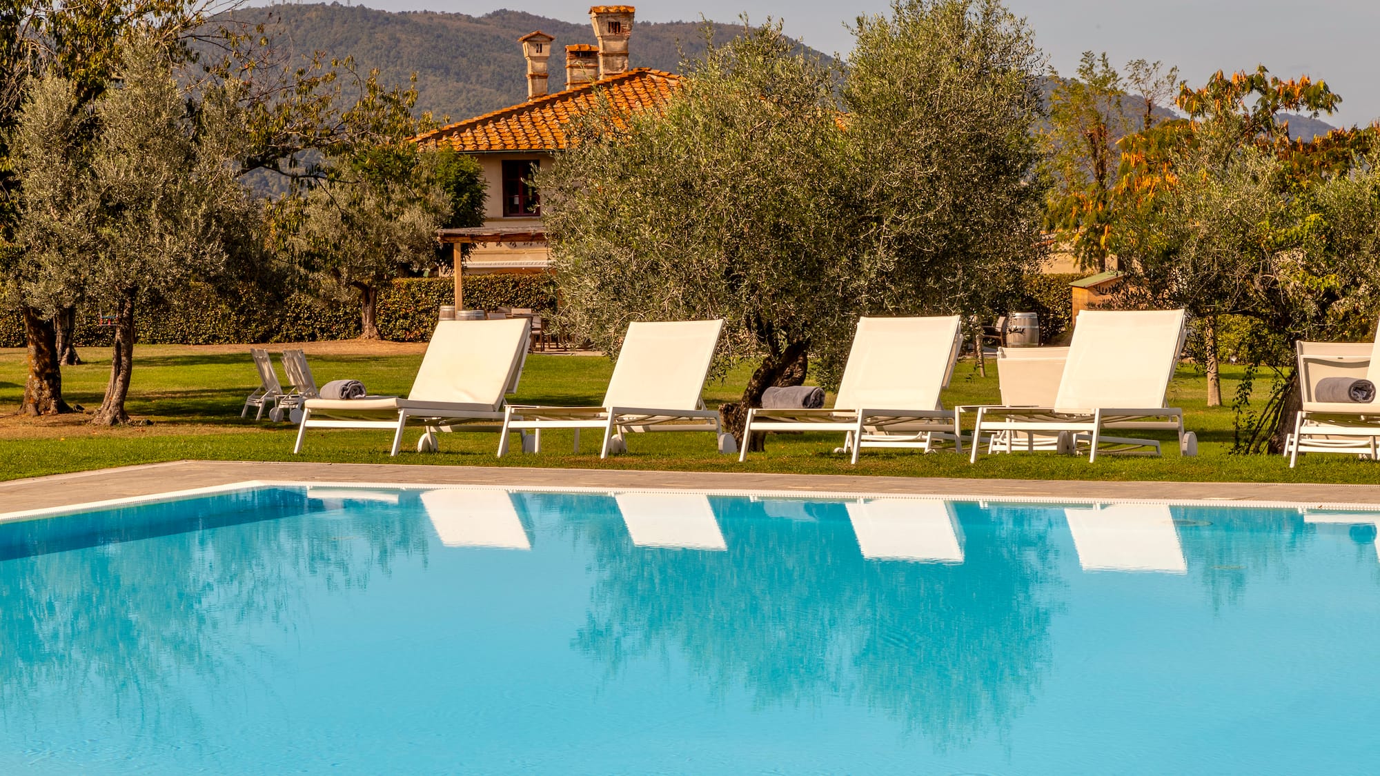 a pool with lounge chairs and trees in the background