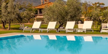 a pool with lounge chairs and trees in the background