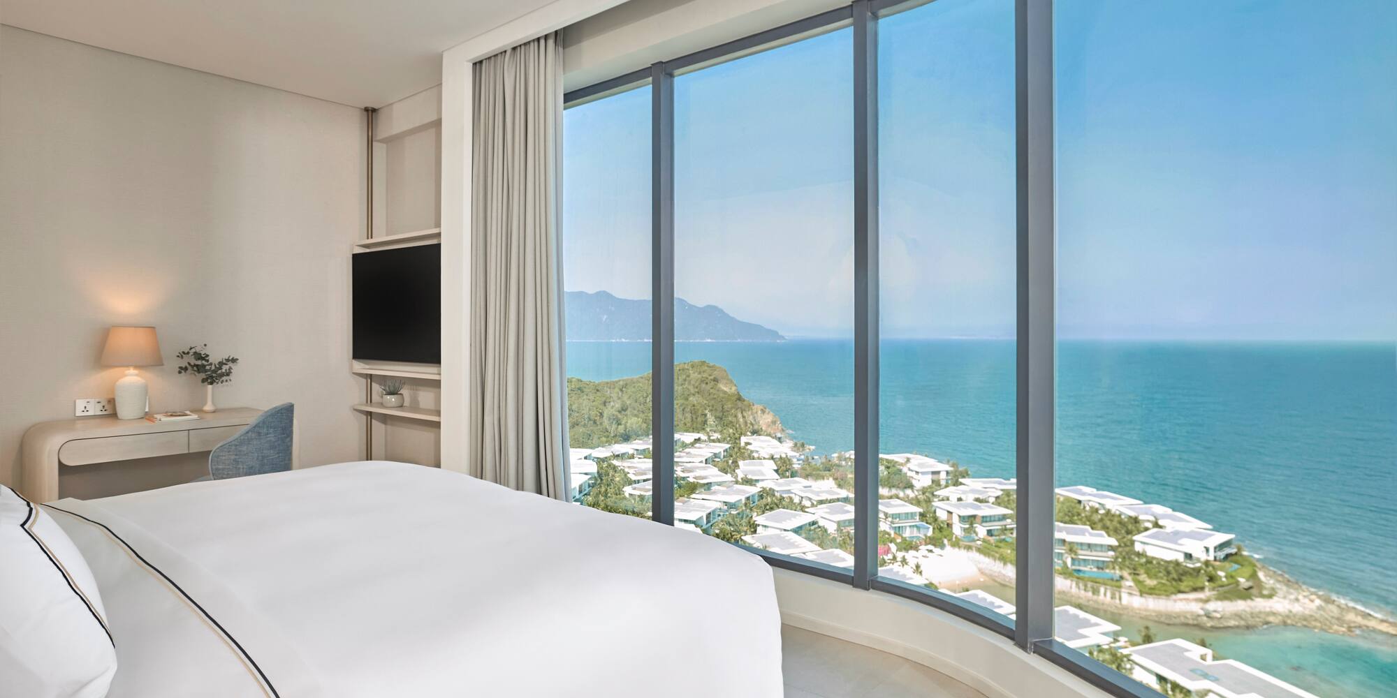 Modern hotel room with panoramic ocean and coastal resort views.