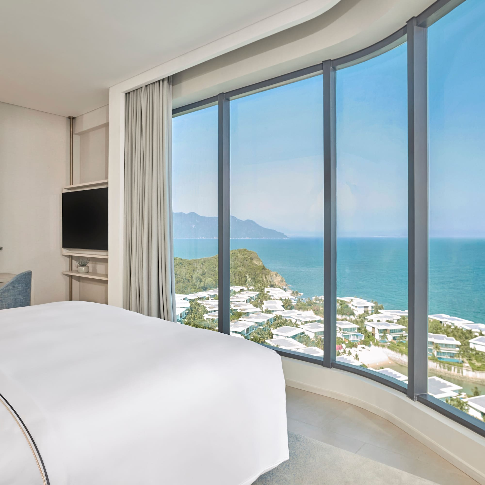 Modern hotel room with panoramic ocean and coastal resort views.