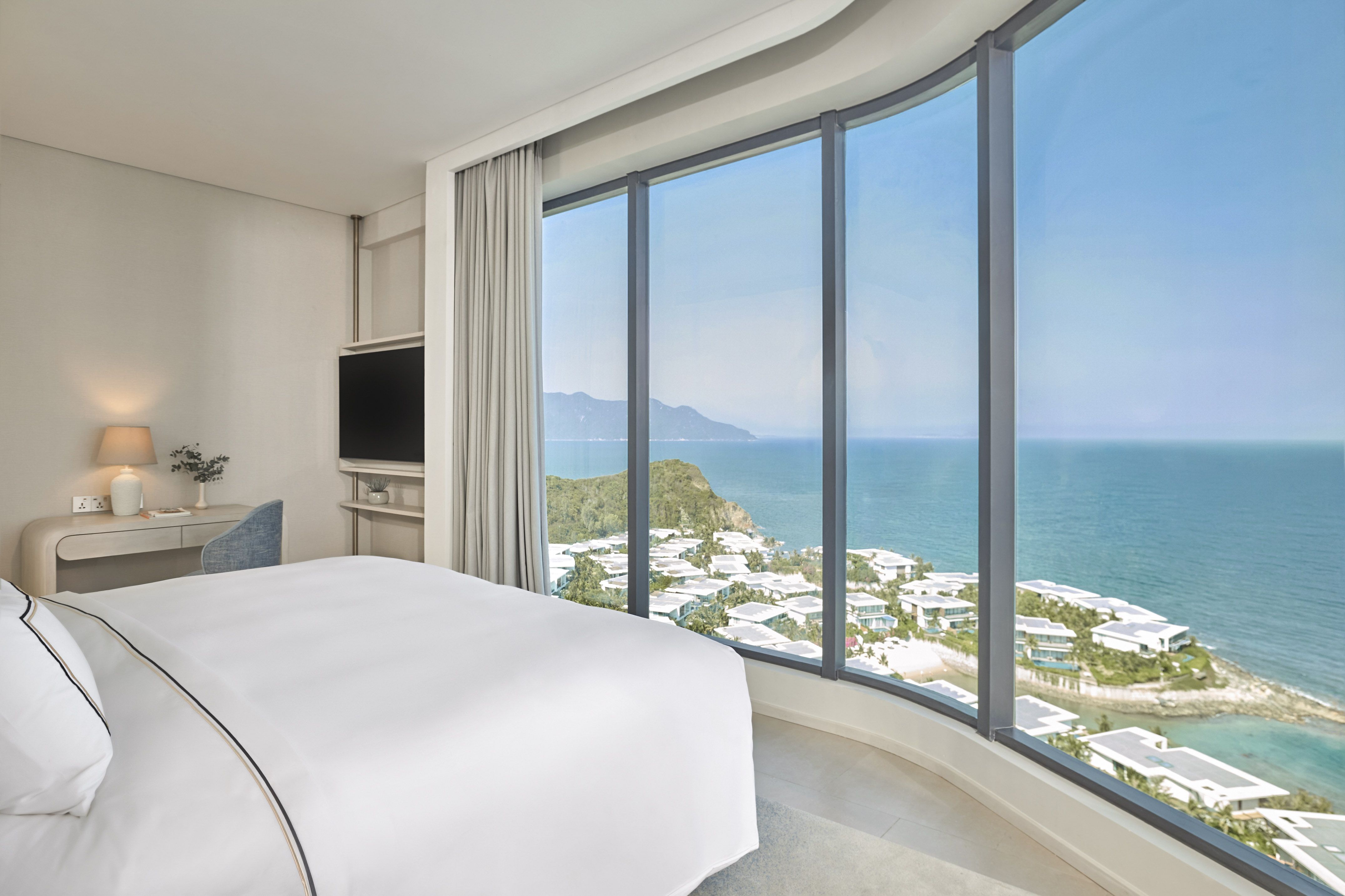 Modern hotel room with panoramic ocean and coastal resort views.