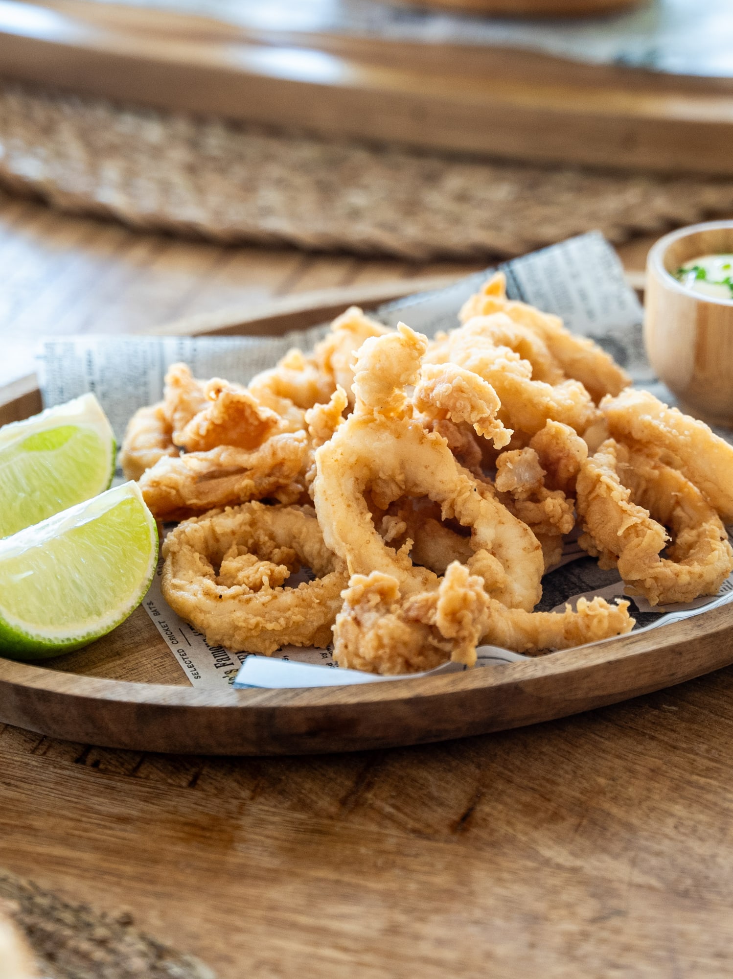 a plate of fried food with lime wedges on a wooden surface