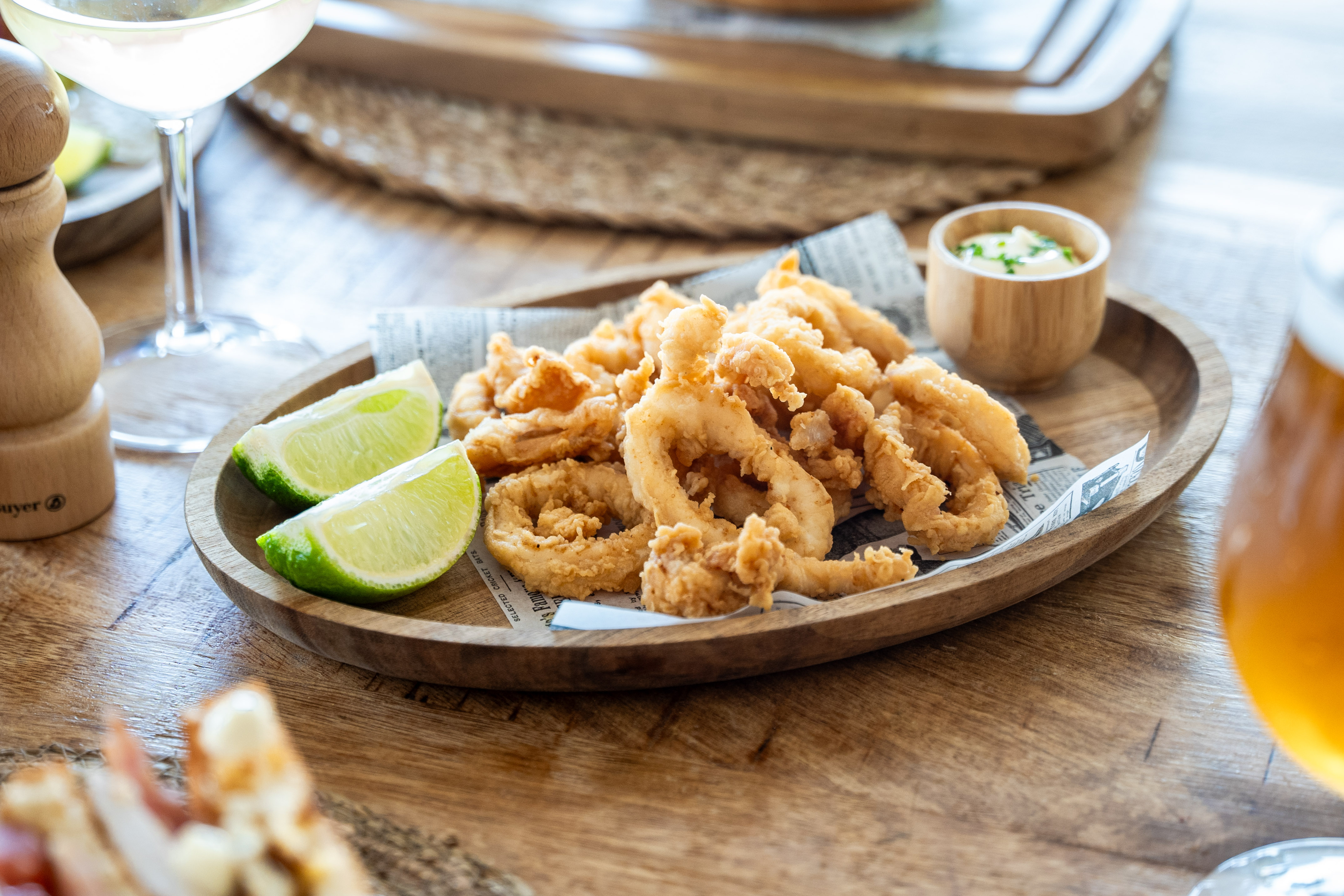 a plate of fried food with lime wedges on a wooden surface