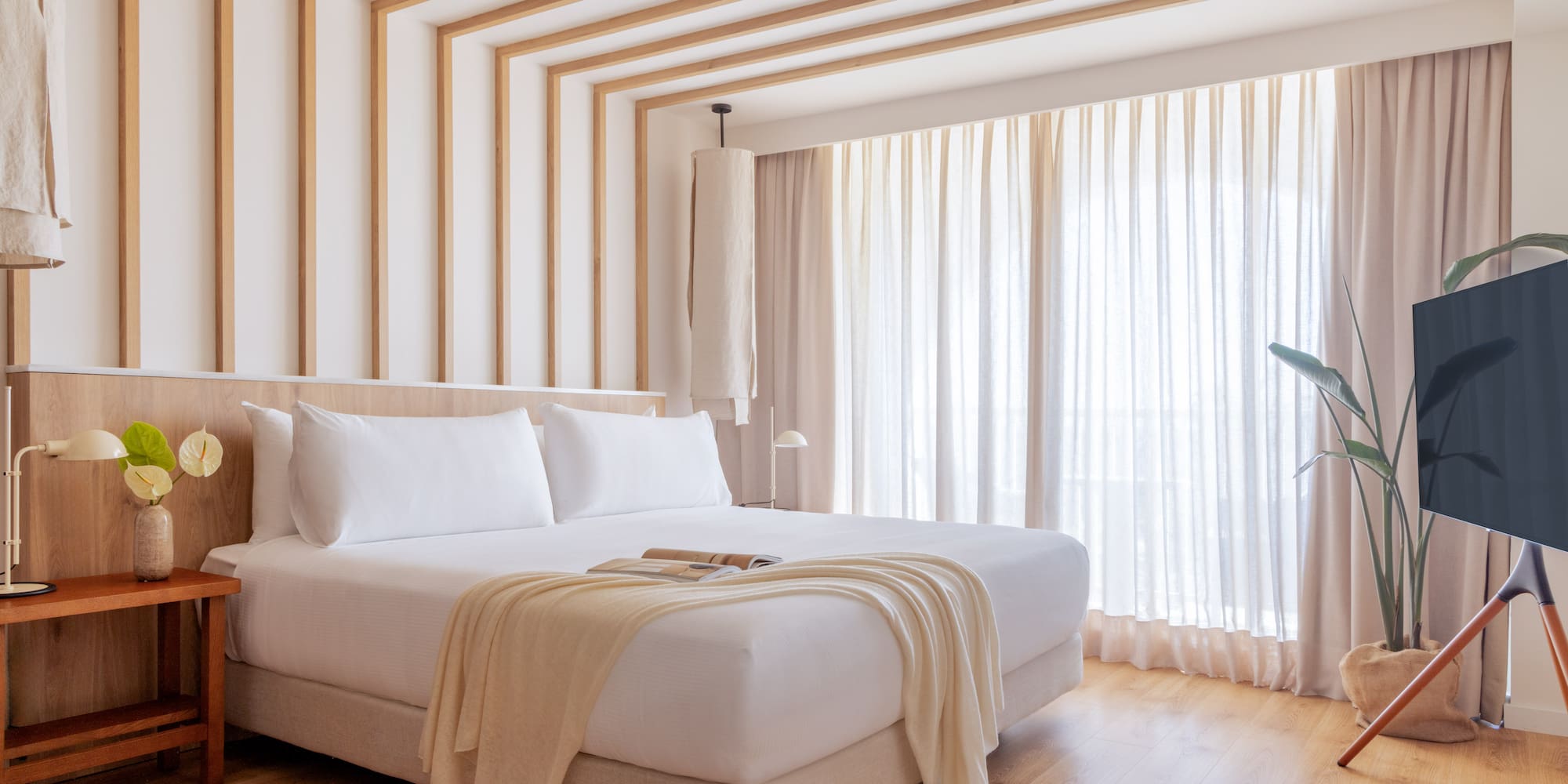 a bed in a room with curtains and a plant