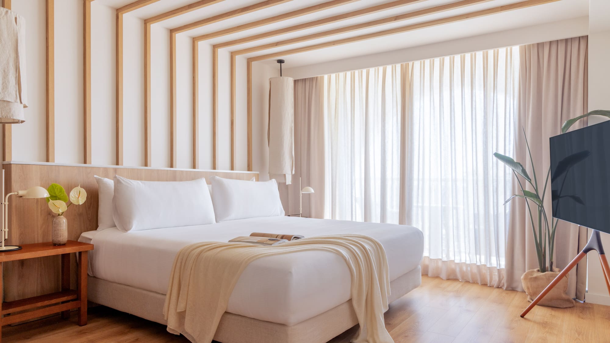 a bed in a room with curtains and a plant