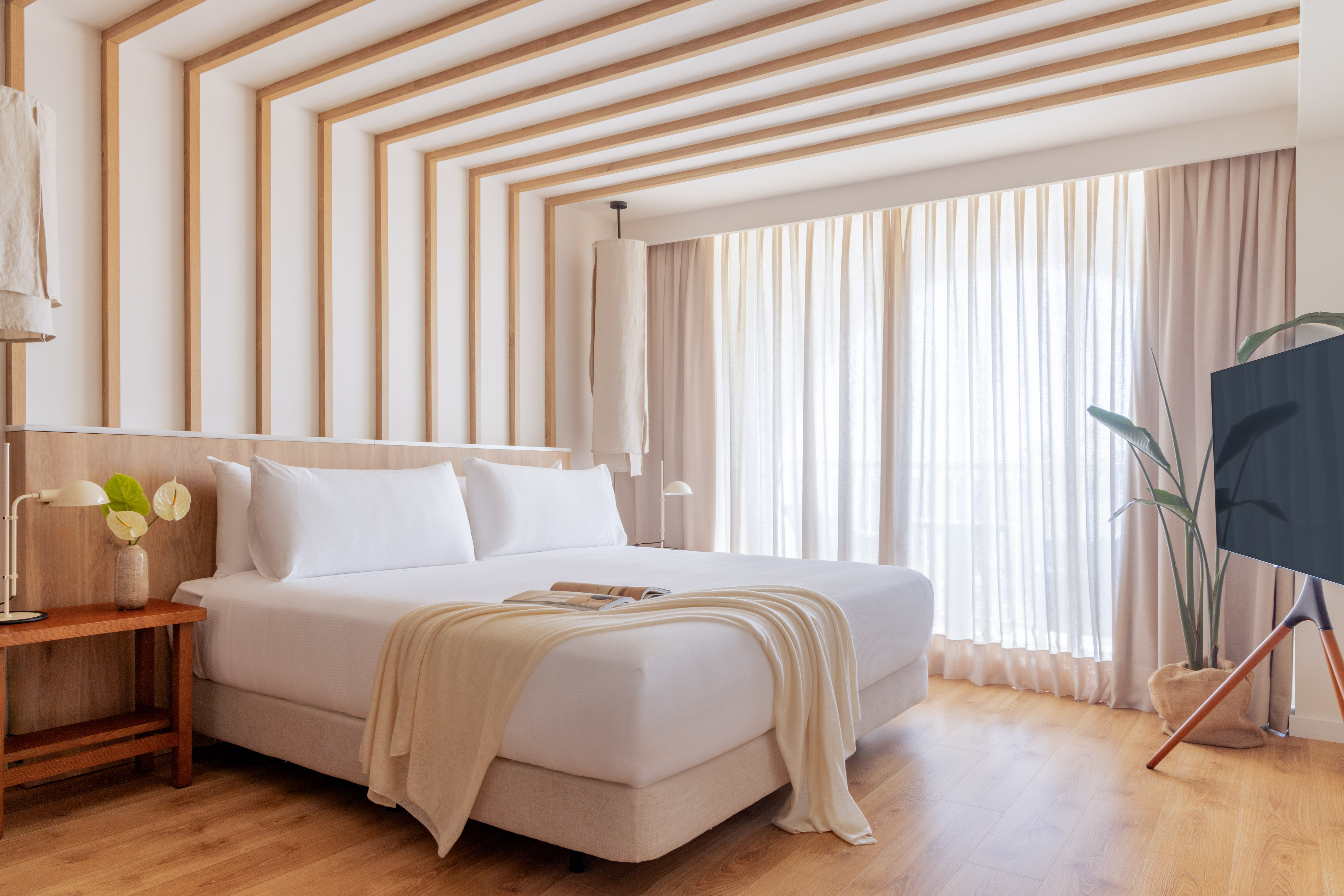 a bed in a room with curtains and a plant